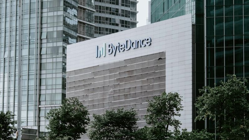 The image showcases a modern office building with a prominent ByteDance logo on its facade. Surrounding greenery and urban architecture are present, highlighting a blend of nature and contemporary design.
