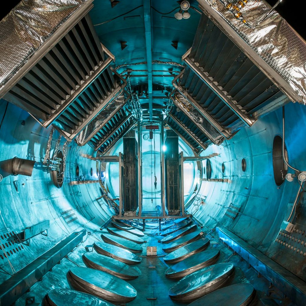 The image depicts the interior of a testing chamber with a futuristic design, showcasing a series of metallic surfaces and equipment surrounded by a blue-lit environment. The space appears engineered for scientific or experimental purposes. — Credit: Photo by NASA on Unsplash