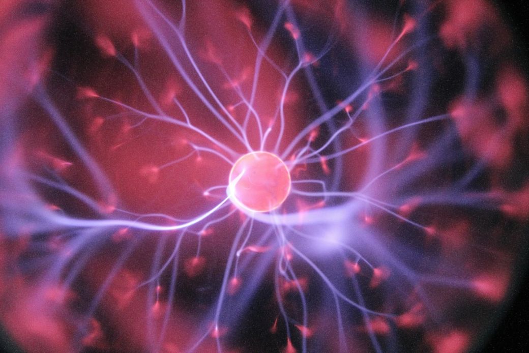 The image depicts a close-up view of a plasma globe, showcasing vibrant electrical arcs extending from a central sphere. The swirling colors and dynamic patterns create a visually striking representation of electrical energy. — Credit: Photo by Hal Gatewood / Unsplash