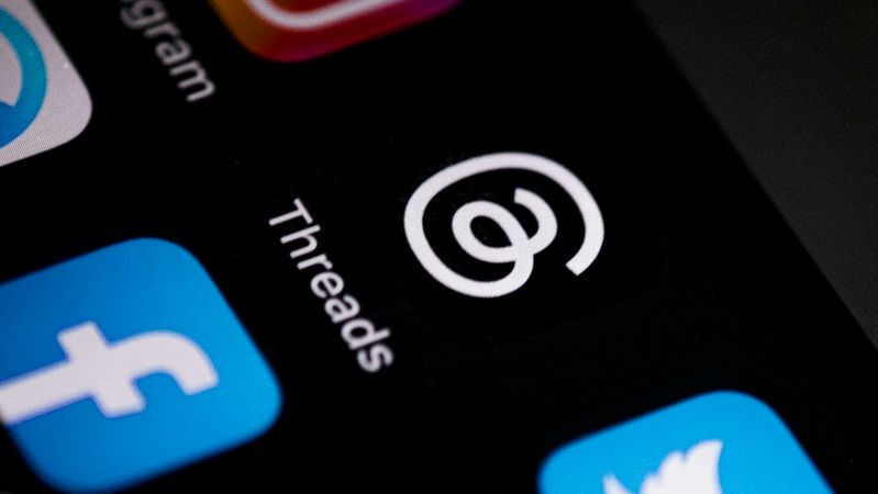 The image shows a close-up view of various social media application icons on a smartphone screen. Notably, the icon for 'Threads' is prominently displayed alongside icons for Instagram, Facebook, and Twitter.