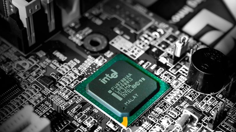 The image displays a close-up view of a computer motherboard featuring an Intel microprocessor. The intricate circuit board includes various electronic components, emphasizing the technology within computer hardware.