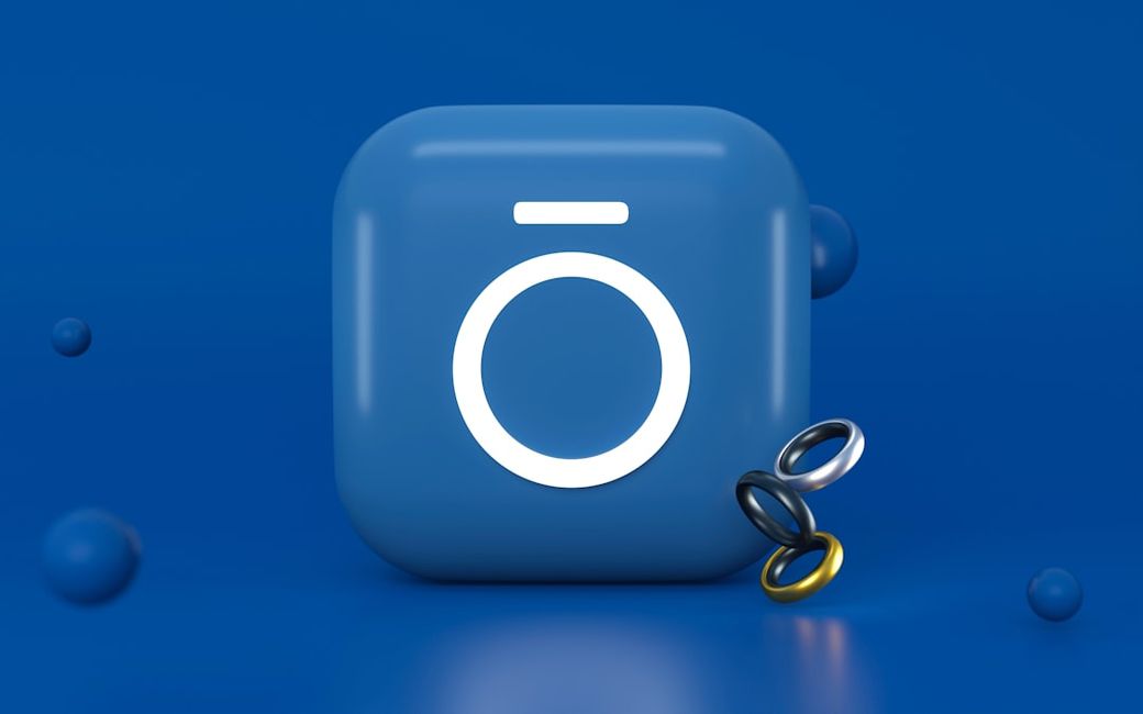 The image features a stylized blue icon with a circular shape and a horizontal line above, surrounded by colorful rings on a matching blue background. The design suggests a modern and digital aesthetic. — Credit: Photo by Mariia Berezovsky on Unsplash