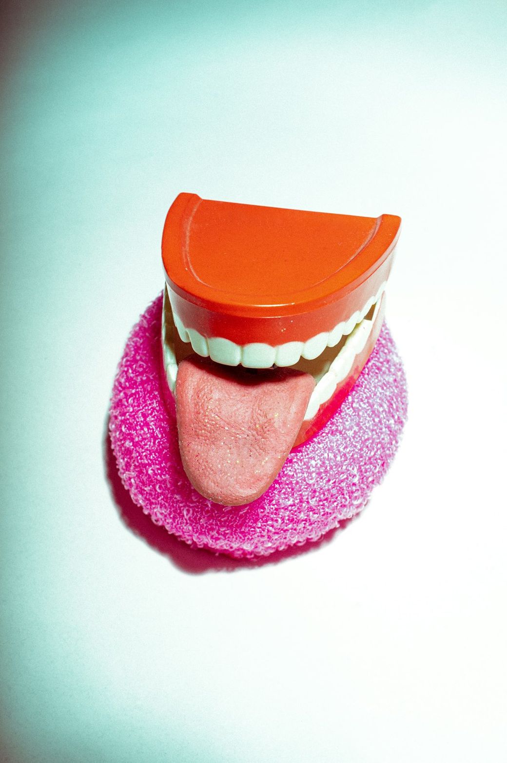 The image features a playful, cartoonish representation of a mouth with a bright orange top and an exaggerated pink tongue, set against a light-colored background. It combines fun colors and shapes indicative of novelty toys or decorations. — Credit: Photo by Girl with red hat on Unsplash