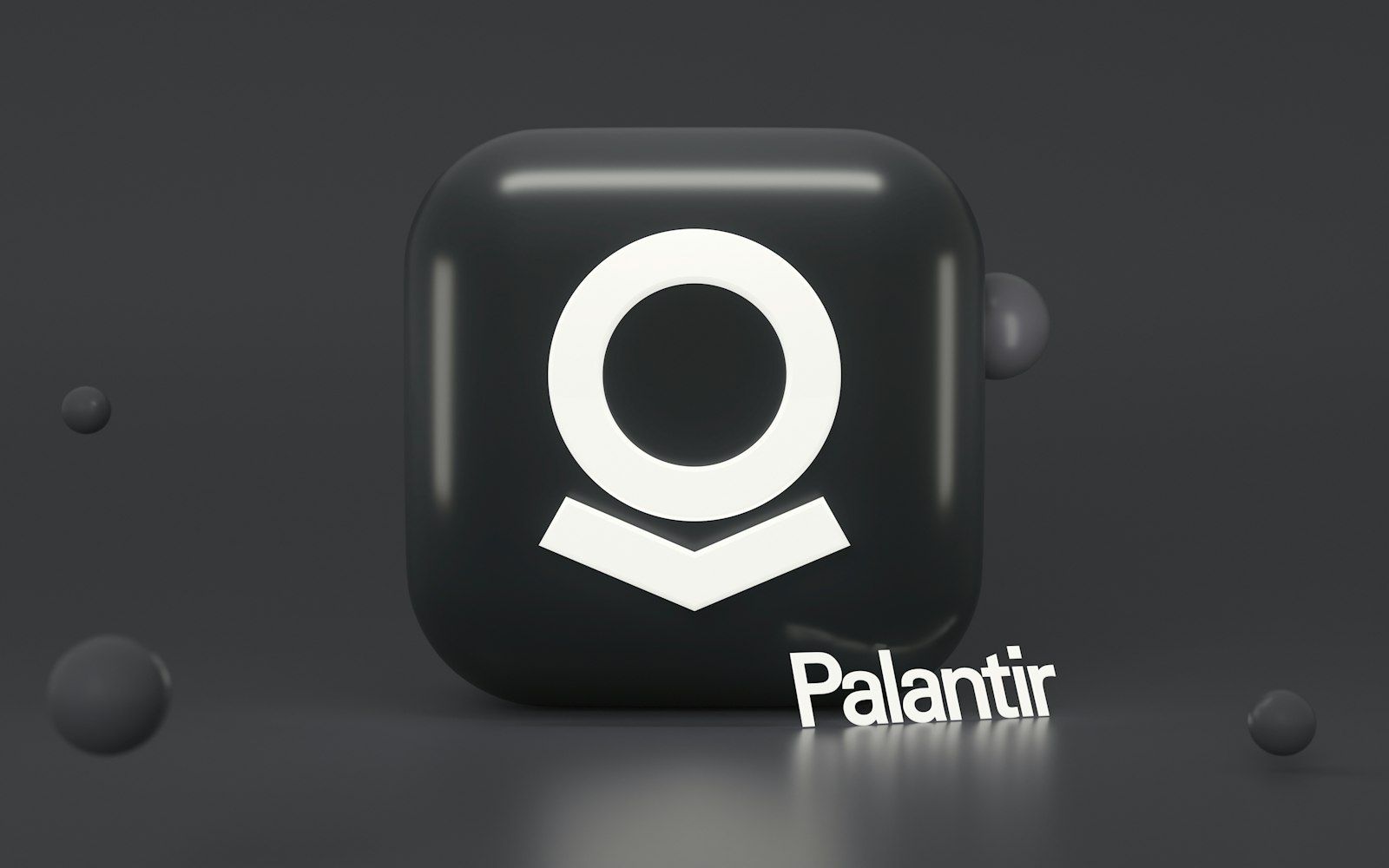 The image features a three-dimensional representation of the Palantir logo on a dark background. Accompanying the logo is the text 'Palantir' displayed prominently in a modern font.