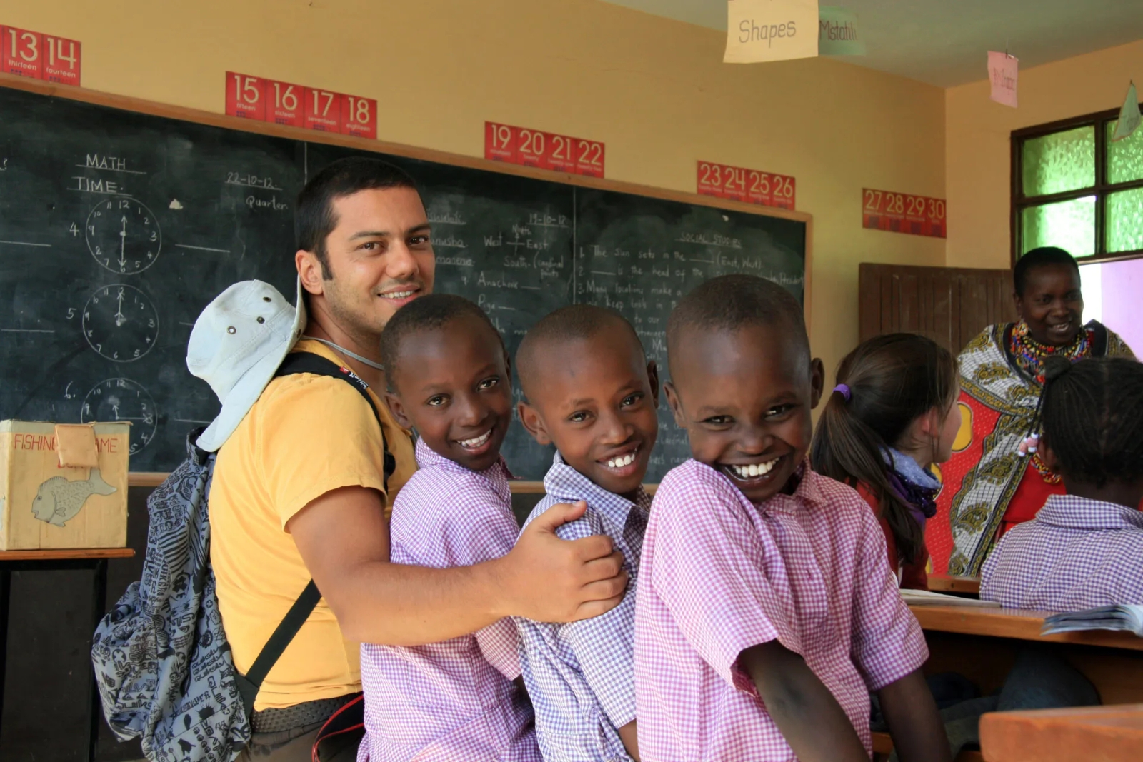 Burak Arik’in 2012’deki ziyaretinde bir sınıfta gülümseyen Kenyalı okul çocuklarıyla paylaştığı mutlu bir an. İnsan bağını yakalayan ve AI’nın taklit edemeyeceği gerçek bir seyahat fotoğrafı.