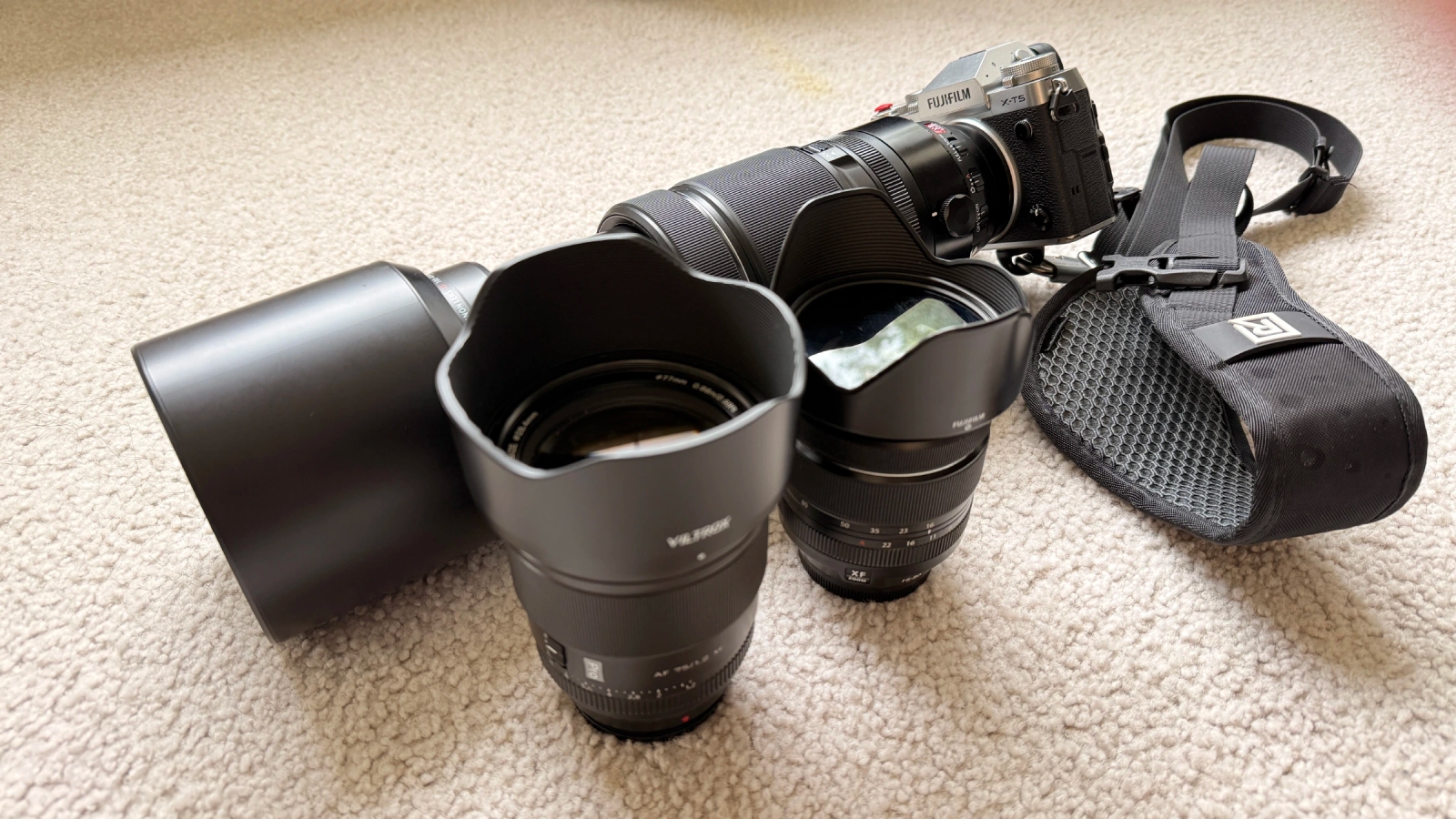 My Fuji X-T5 travel kit with three lenses: FUJIFILM XF 100-400mm telephoto mounted on body, Viltrox 75mm f/1.2 portrait lens, FUJIFILM XF 16-80mm f/4 all-around zoom, and BlackRapid Curve Breathe strap