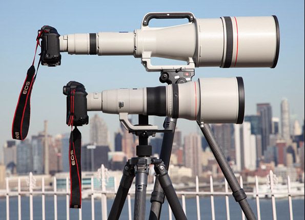 Şehir silueti arka planında tripodlara monte edilmiş Canon EF 800mm f/5.6L IS USM süper telefoto prime objektifler, profesyonel vahşi yaşam ve spor fotoğrafçılığı ekipmanı