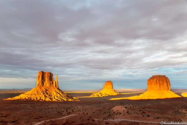 Göz kamaştırıcı Monument Valley gün batımı, kumtaşı oluşumlarını aydınlatan canlı turuncu ve mor gökyüzü ile.