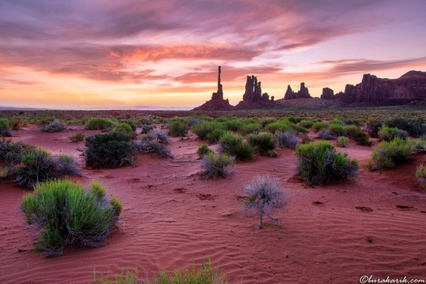 Sakin Monument Valley şafağı, altın sabah ışığının ikonik kumtaşı tepeleri üzerinde sıcak bir parıltı oluşturmasıyla.