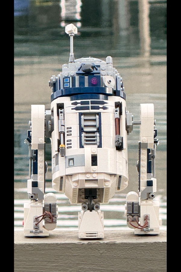 iPhone 16 Pro at 18x digital zoom showing visible artifacts, noise, and busy background on LEGO R2-D2 subject
