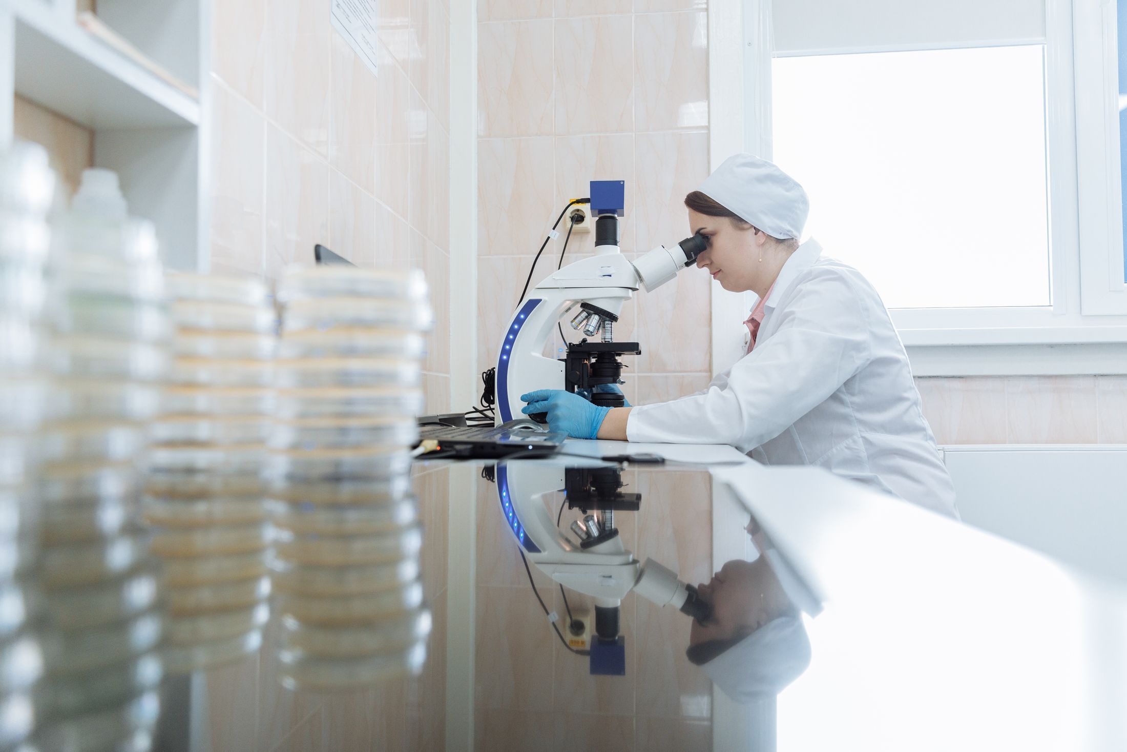Scientist examining samples through a microscope in a bright laboratory