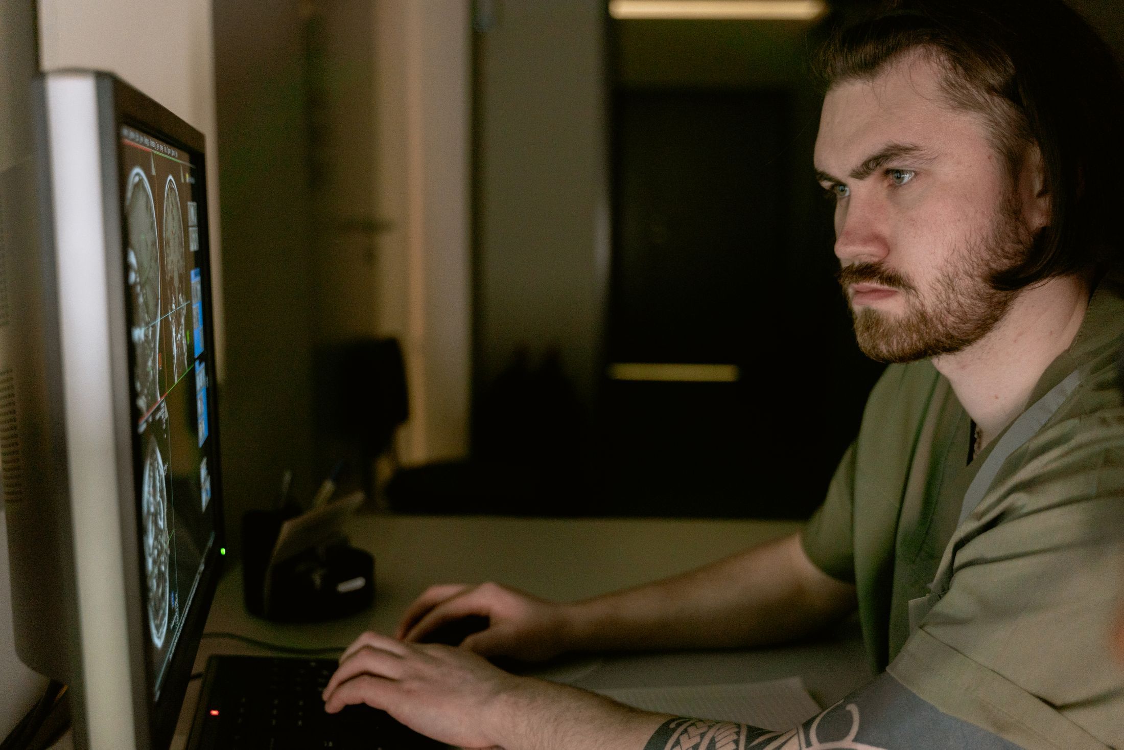 Radiologist intensely studies CT scan results on computer monitor in healthcare setting.