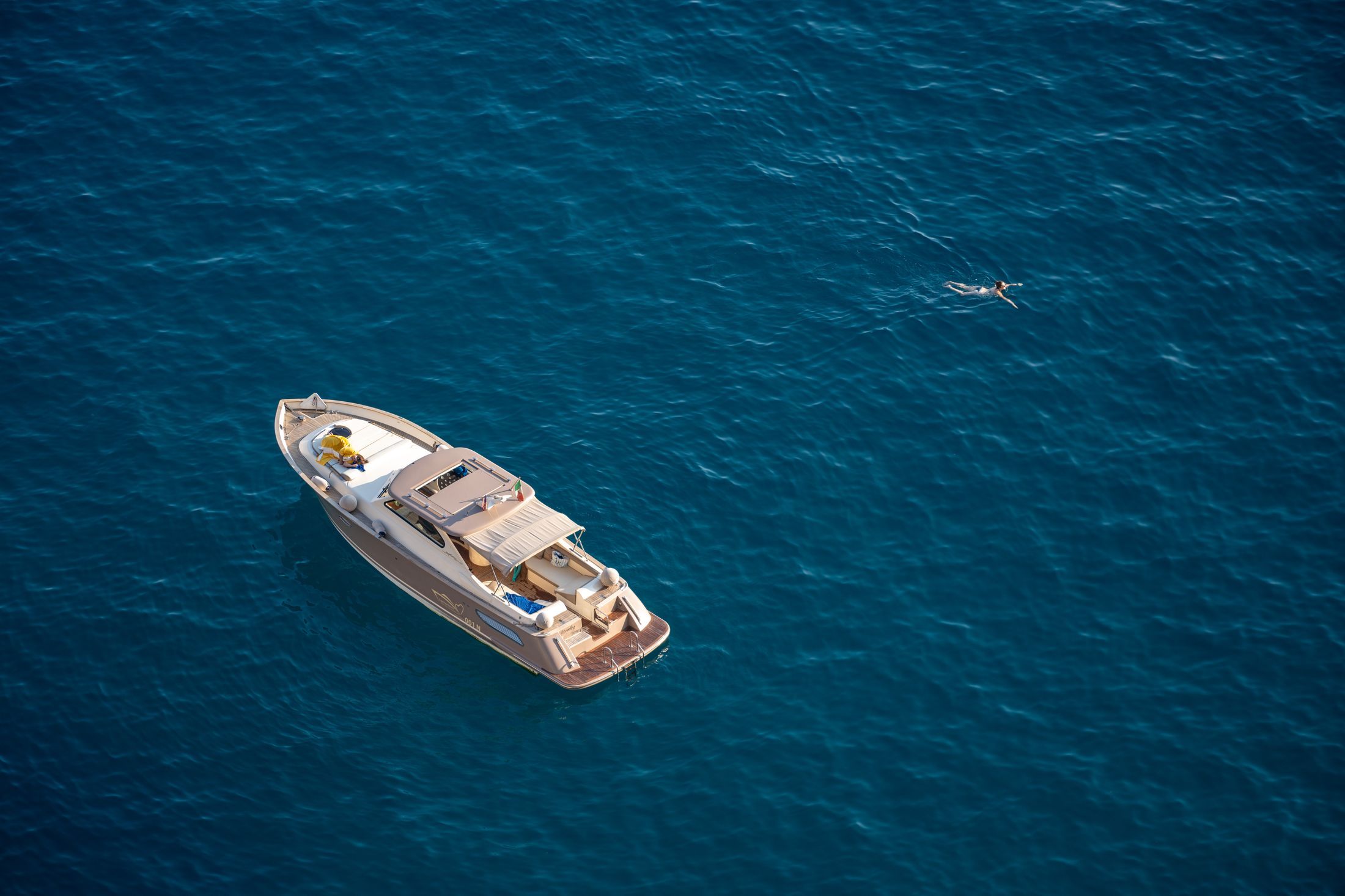 A luxurious motor yacht and a swimmer in the clear blue sea near Capri, Italy.