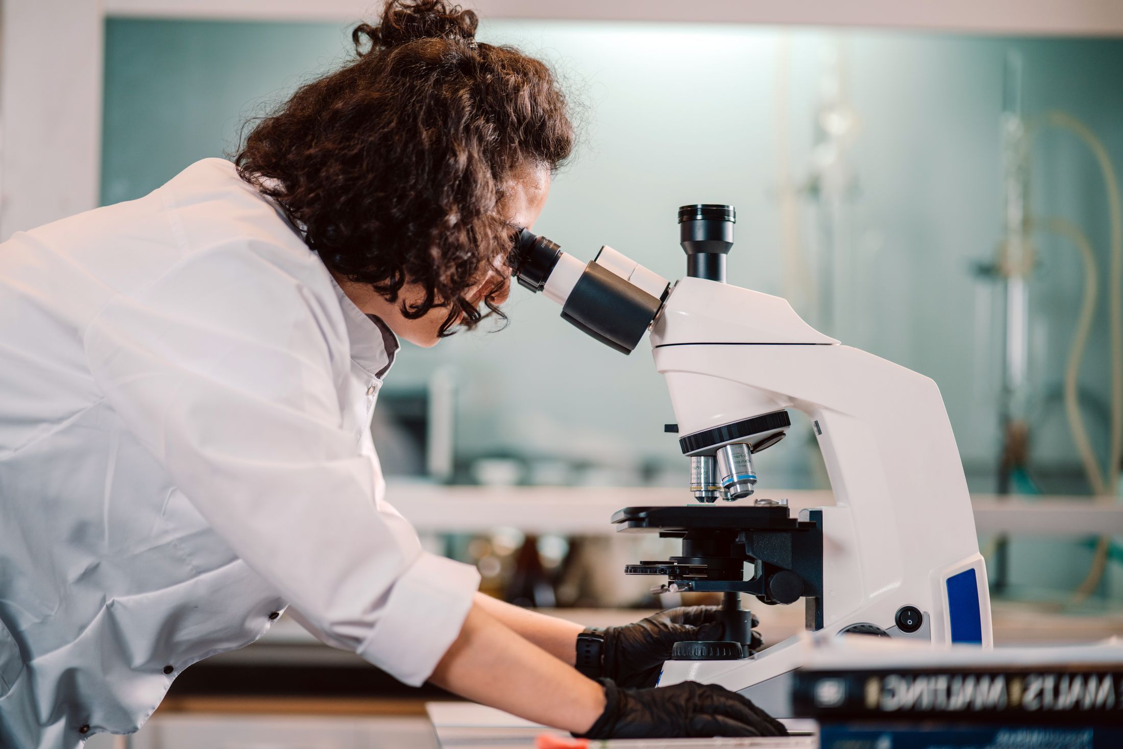 A woman scientist using a microscope in a laboratory setting.
