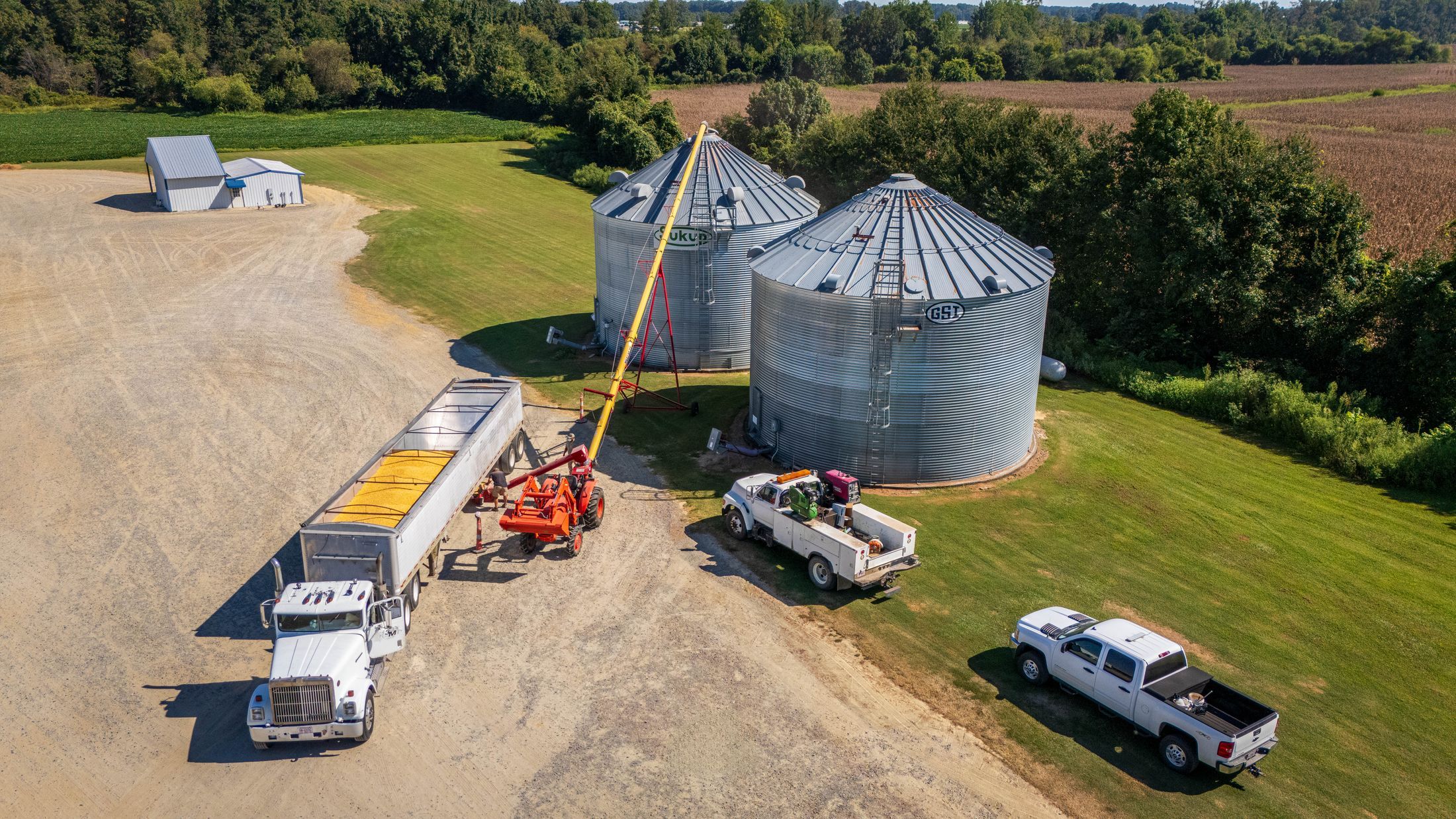 Aerial photograph capturing grain silos, trucks, and agricultural machinery on a North Carolina farm.