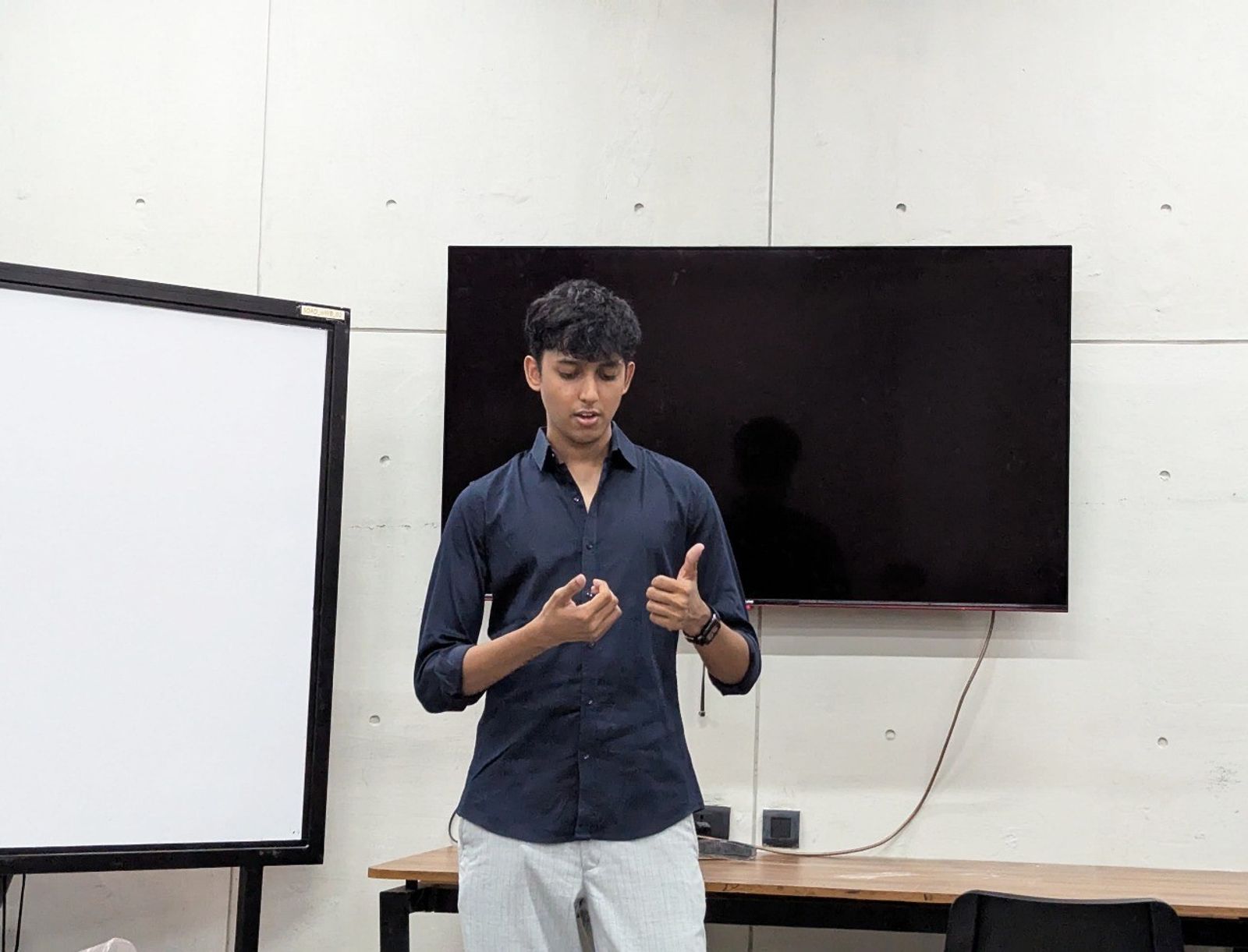 Sid presenting in front of a screen and a whiteboard