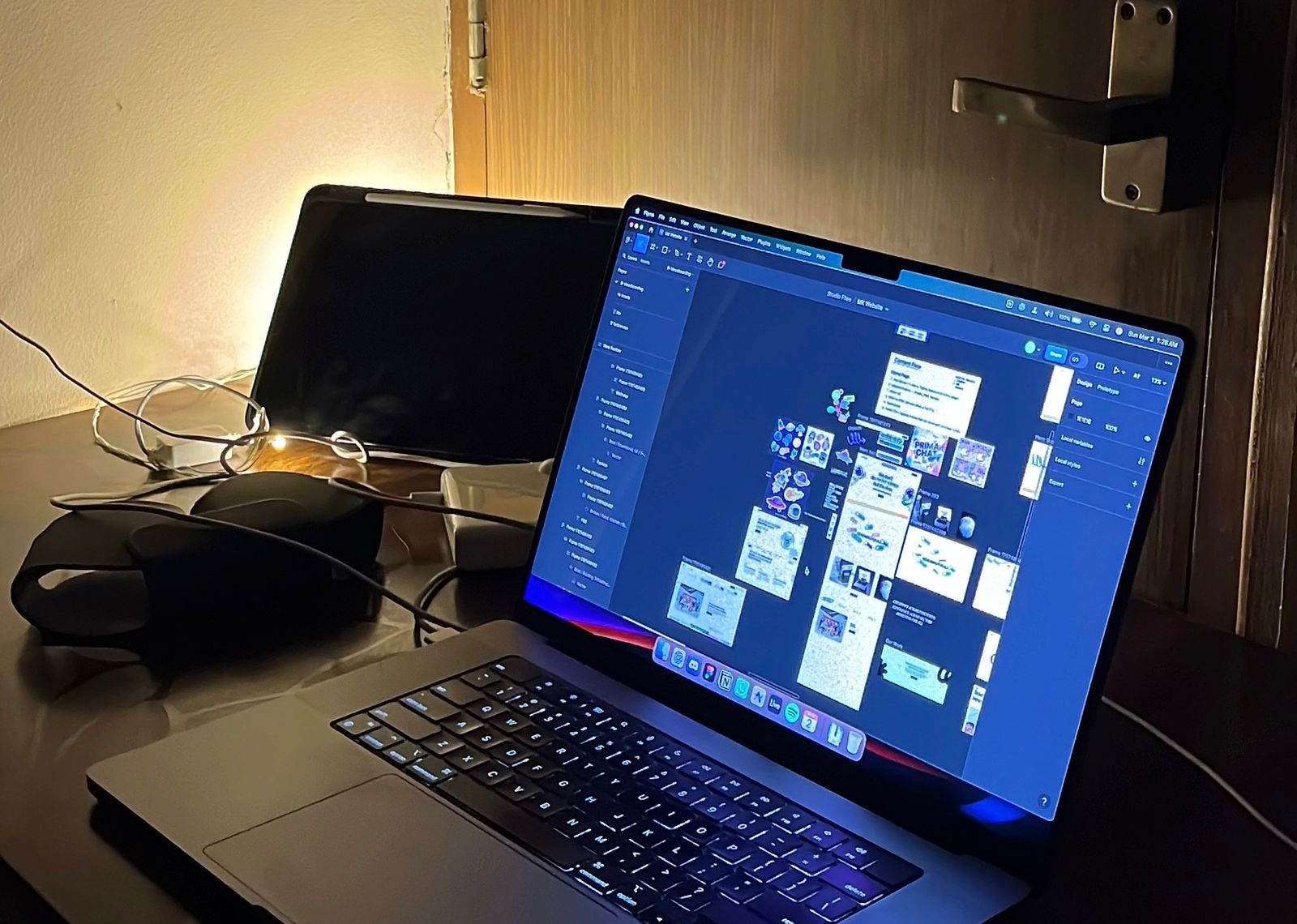 A laptop on a desk at night with a Figma file of many screens open