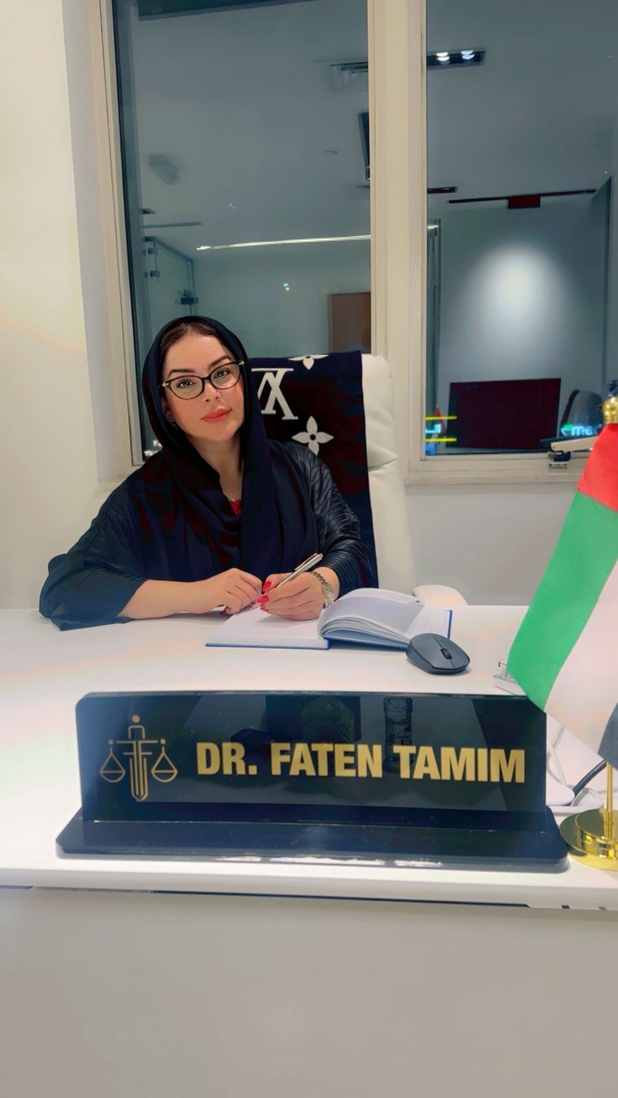 Dr. Faten with an open document at her desk