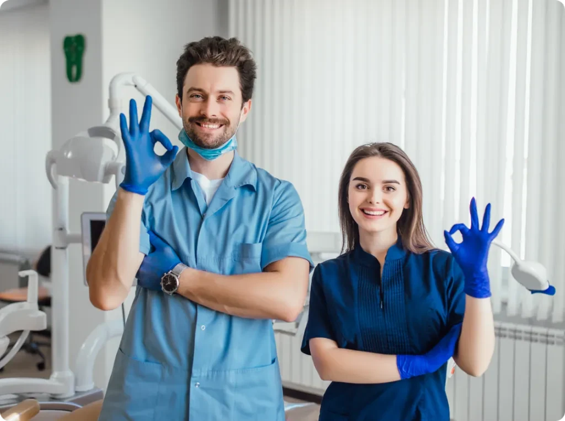 Two smiling dental professionals giving an OK sign