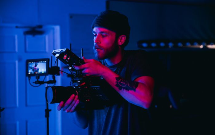 Videographer operating a professional cinema camera rig with monitor on a production set