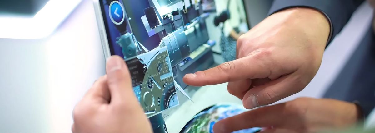 Close-up at EIAS 2026: one hand holds a tablet showing a 3D spacecraft model, another points at the screen
