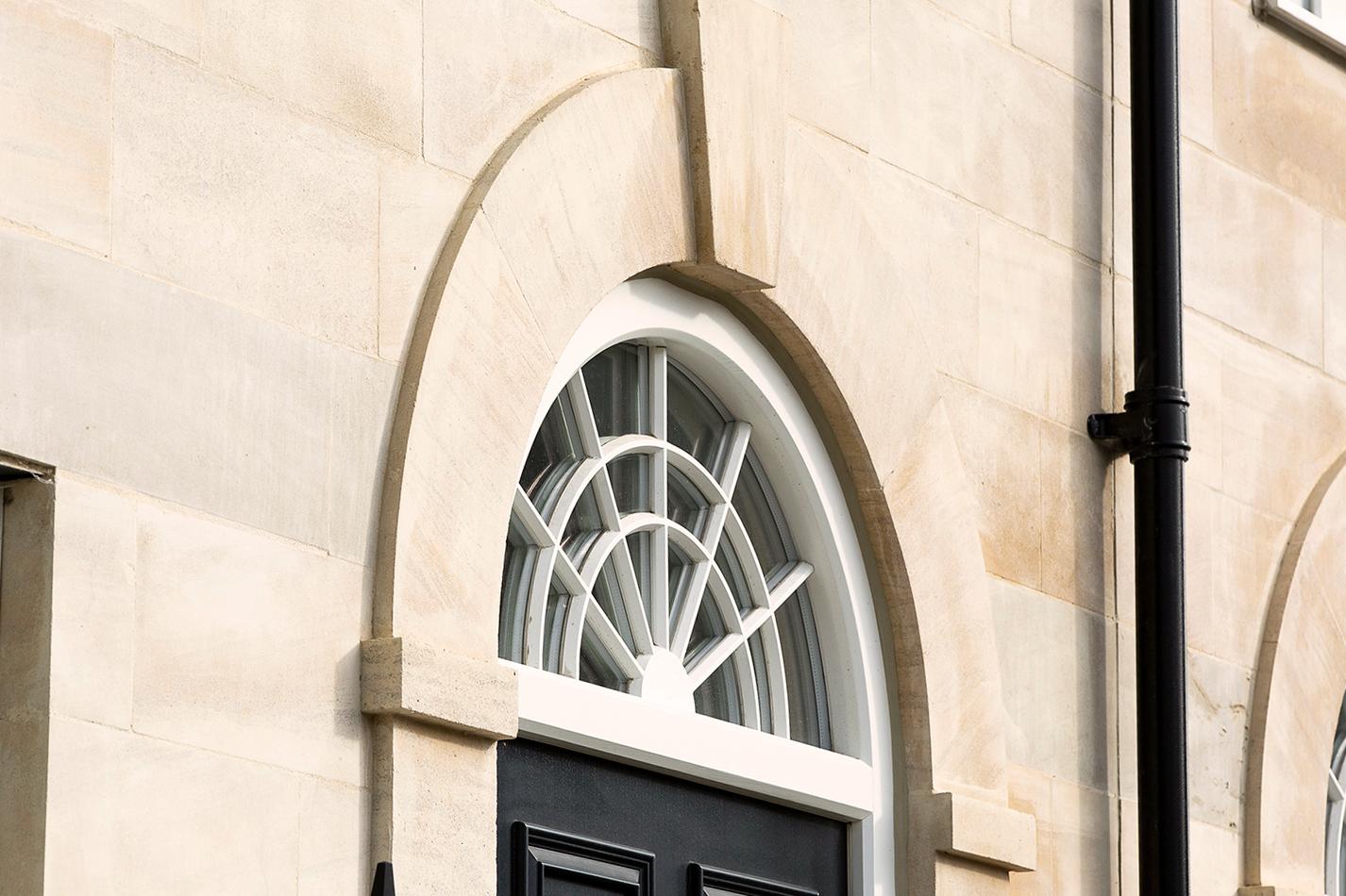 A fanlight window above the door and stone dressings around the arch