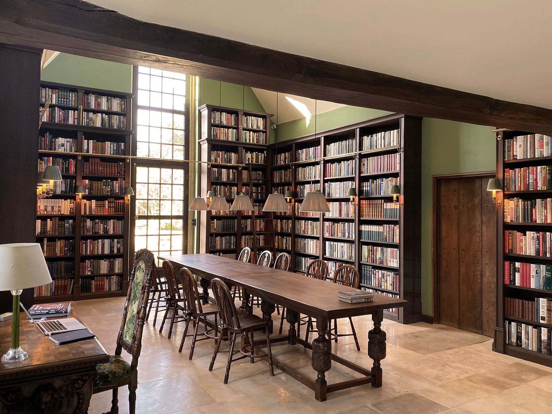 New library with dark wood bookcases and a long table and 10 chairs