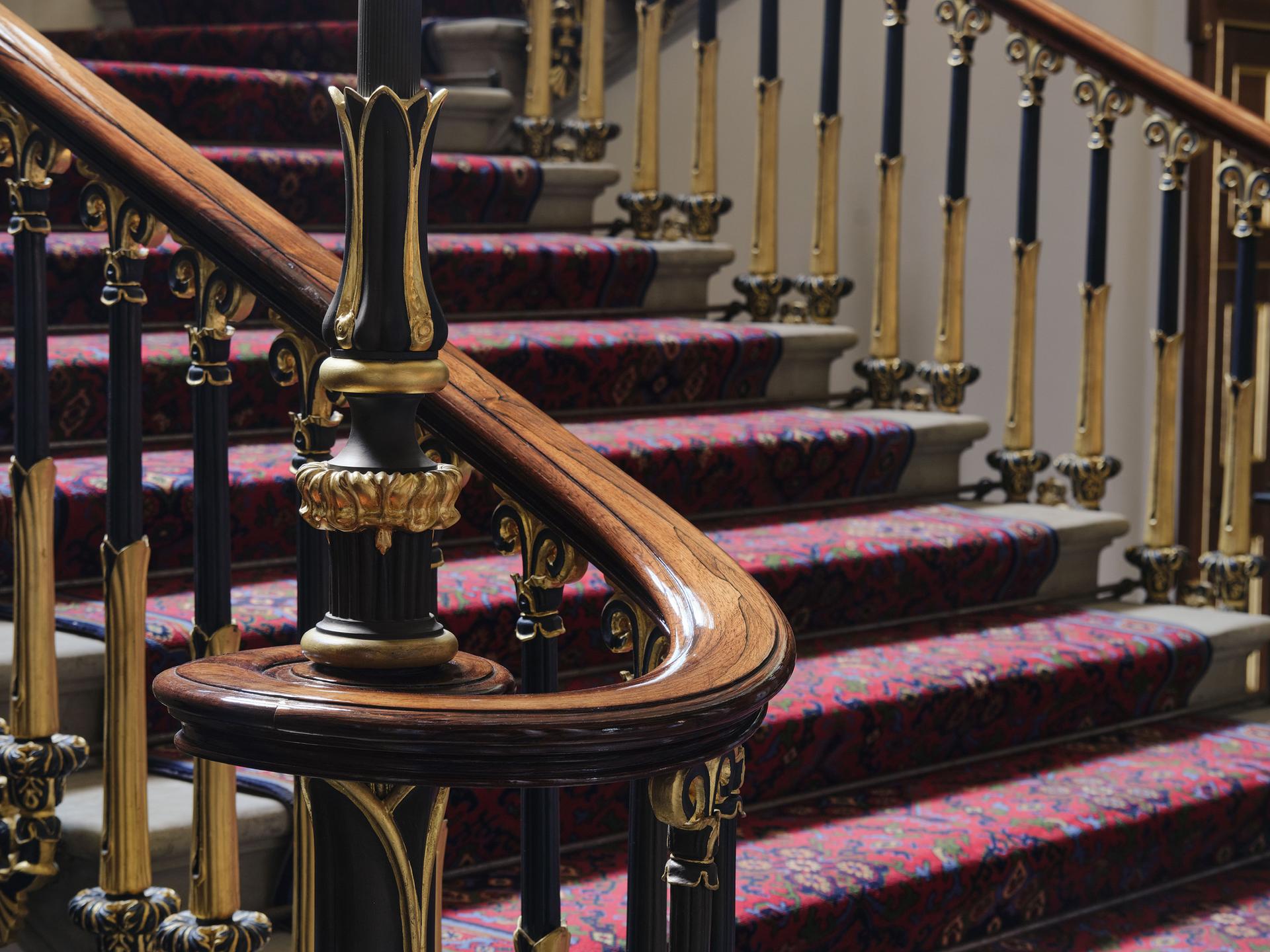 Staircase with curved handrail and black and gold leaf spindles