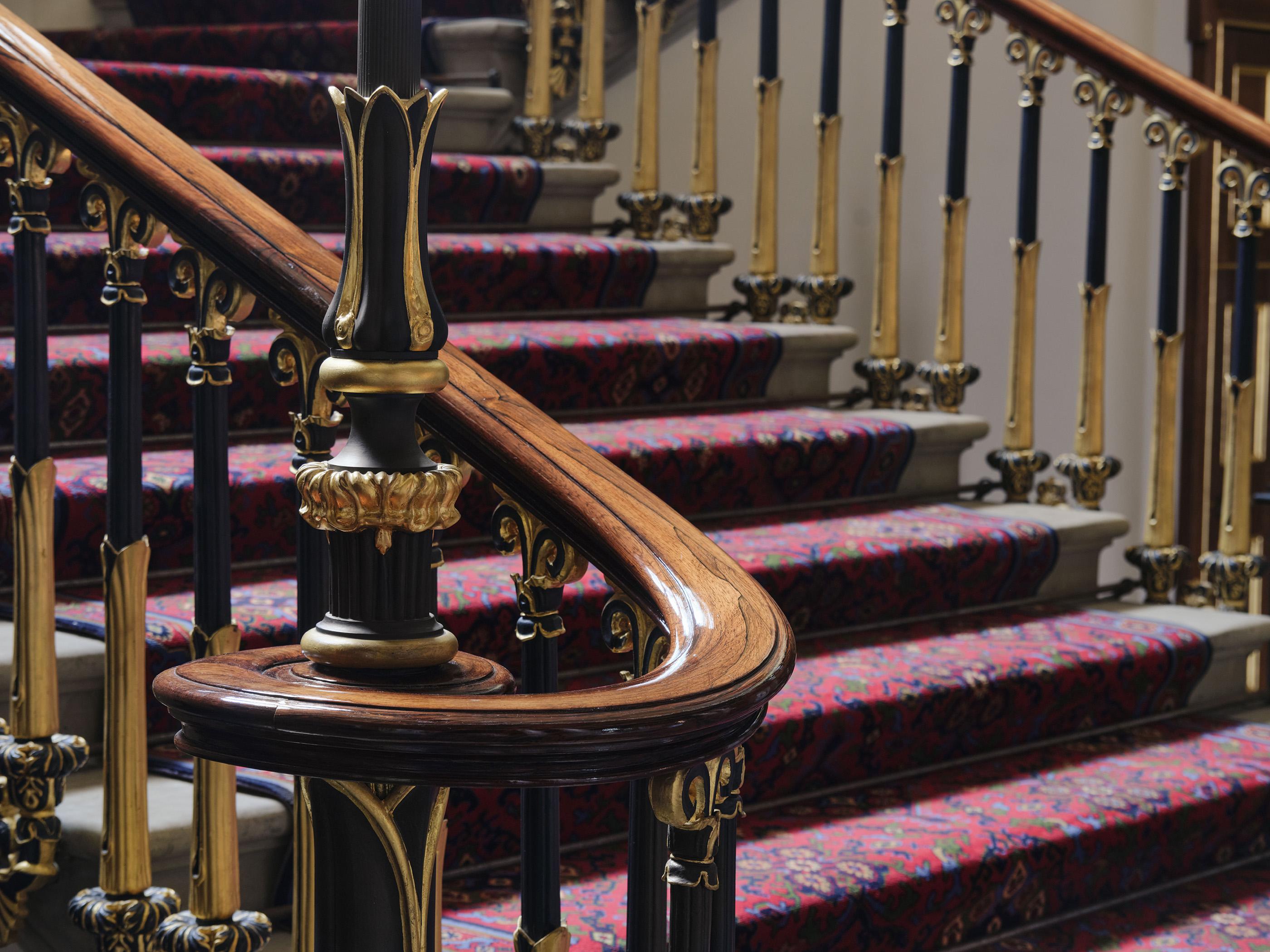 Staircase with curved handrail and black and gold leaf spindles