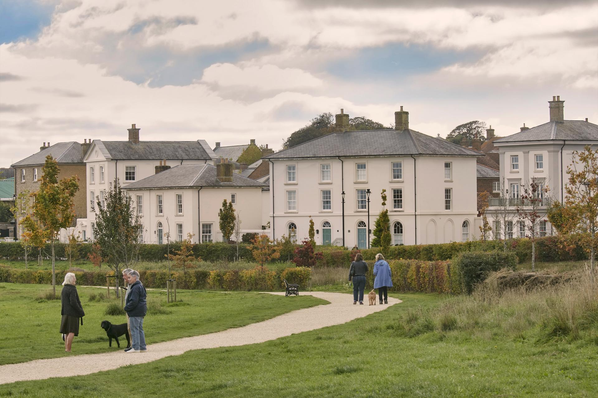 Dog walkers on The Great Field, view across to Georgian style houses along Dukes Parade