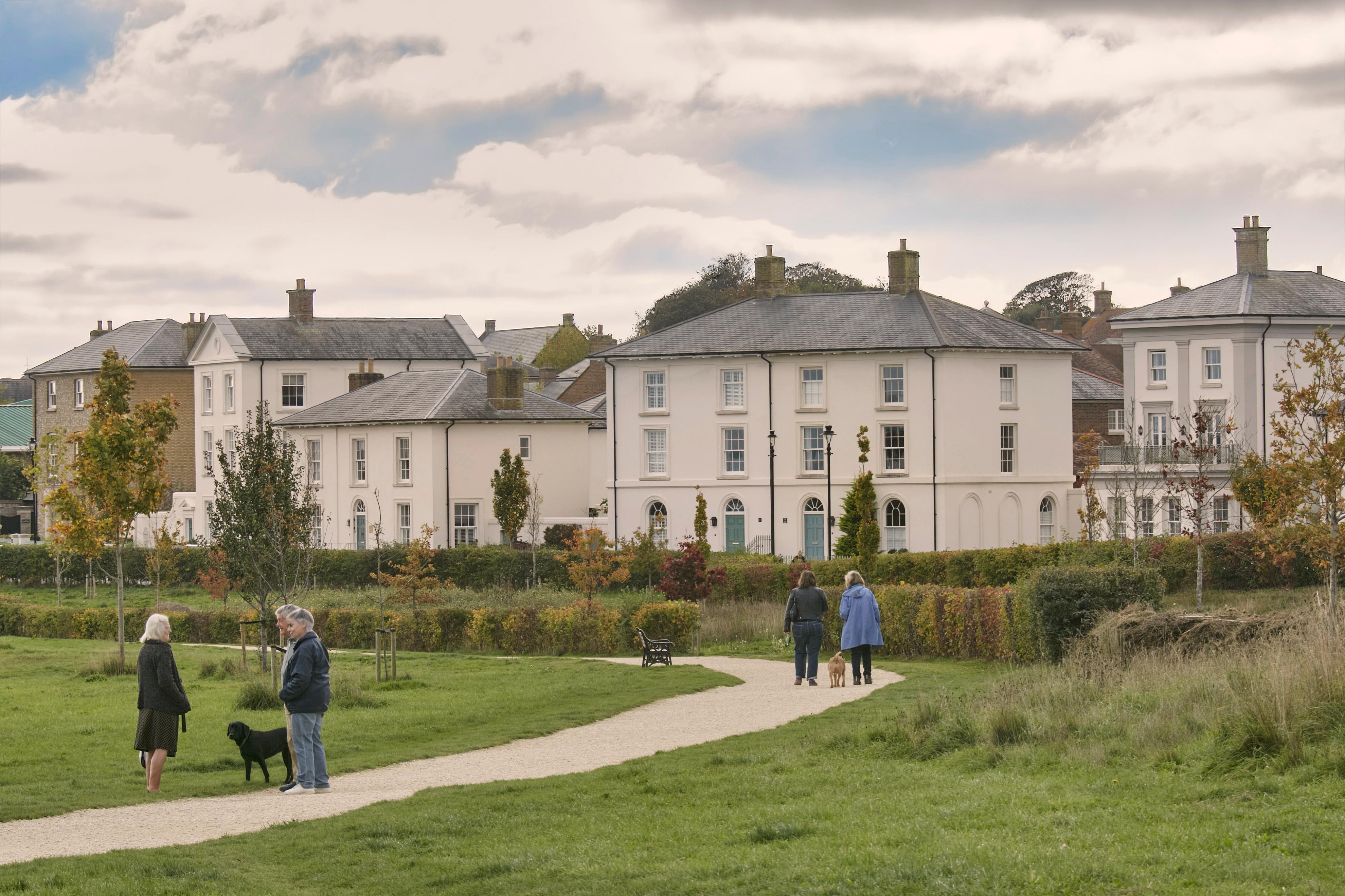 Dog walkers on The Great Field, view across to Georgian style houses along Dukes Parade