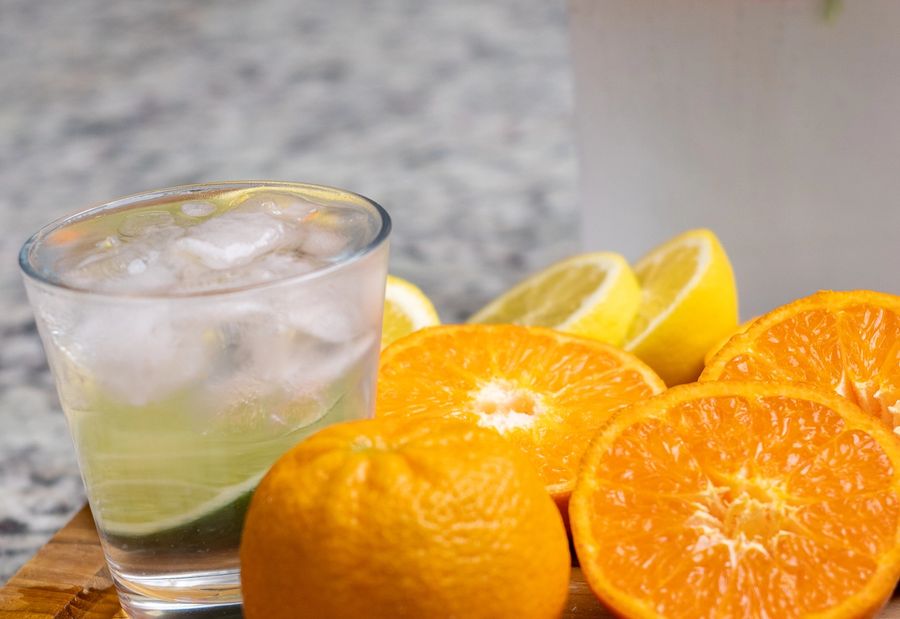 A clear glass with ice and sliced citrus on a wooden board. A cold drink, composed.