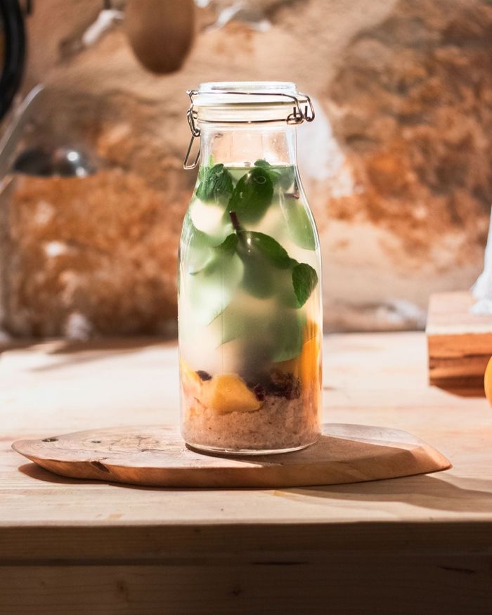 A swing top bottle of homemade water kefir, kefir grains settled at the bottom with fruit pieces and fresh mint inside.