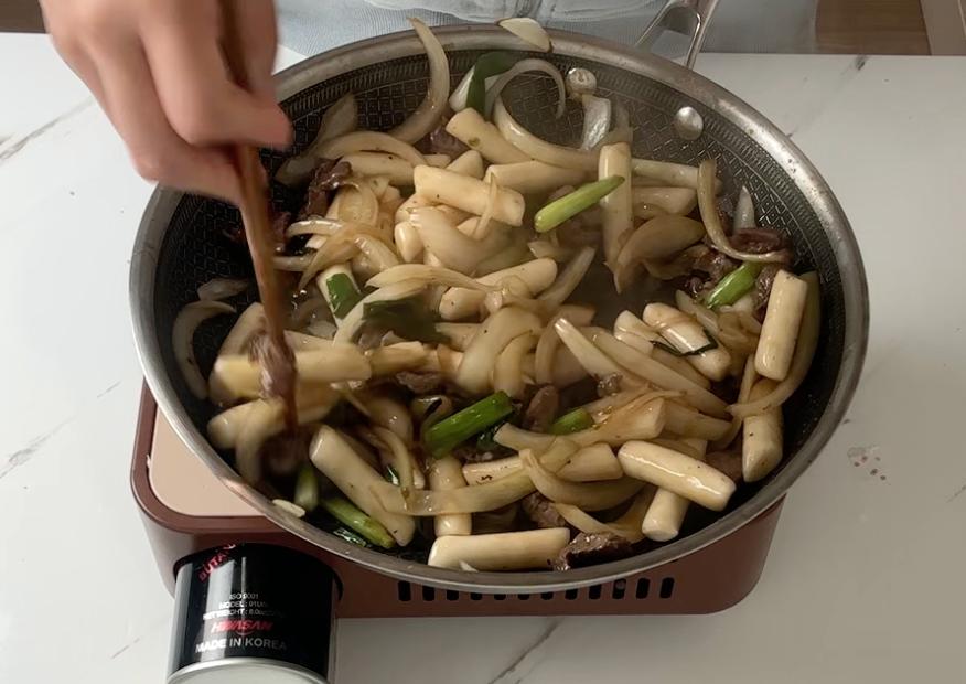stir-frying the vegetables, beef and rice cakes