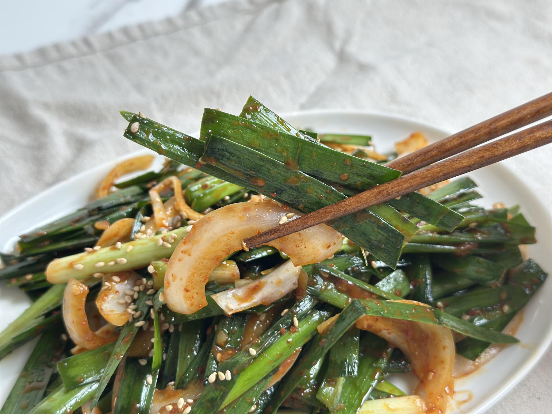 Holding chive kimchi with chopsticks