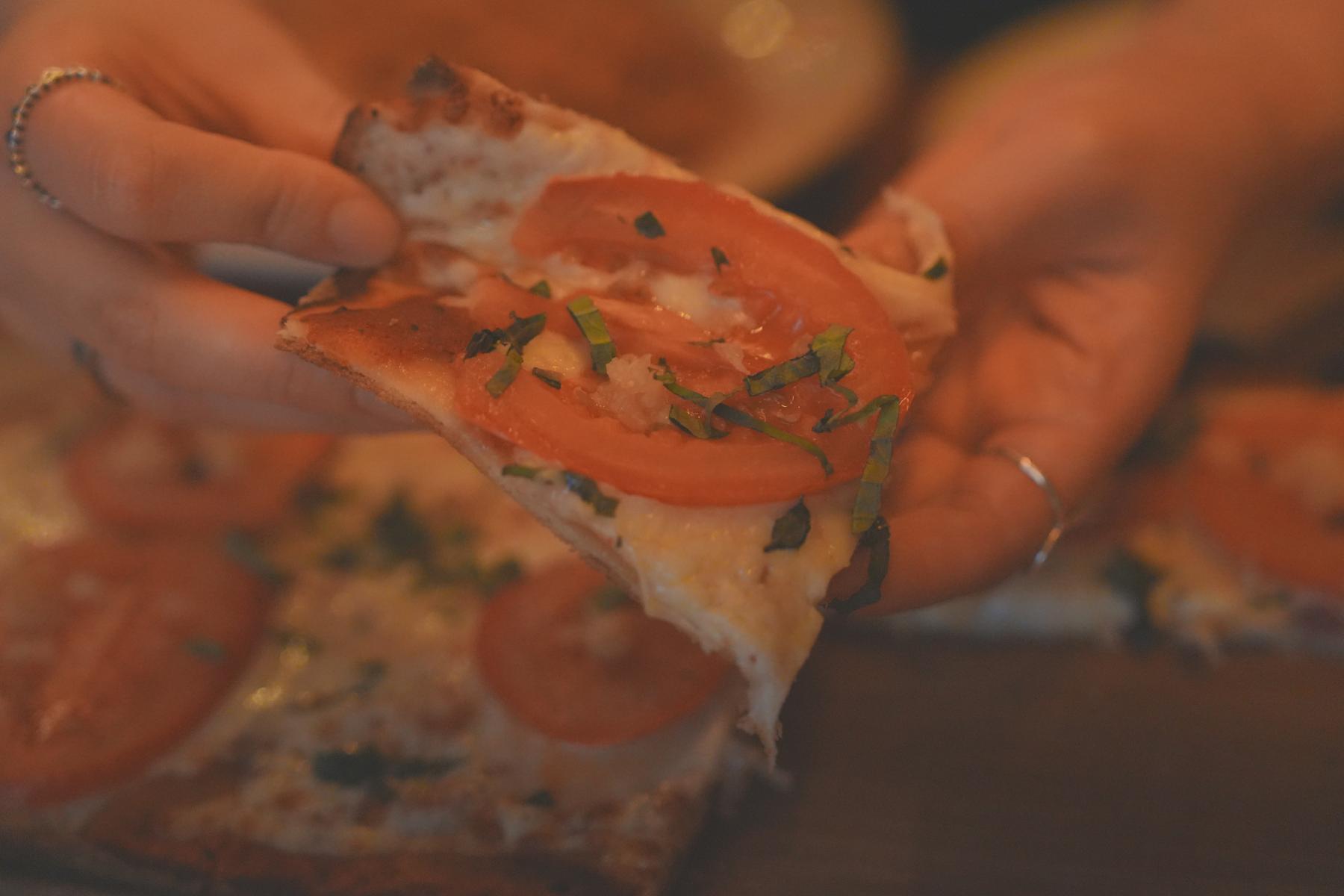 Holding Roma Tomato Pizza