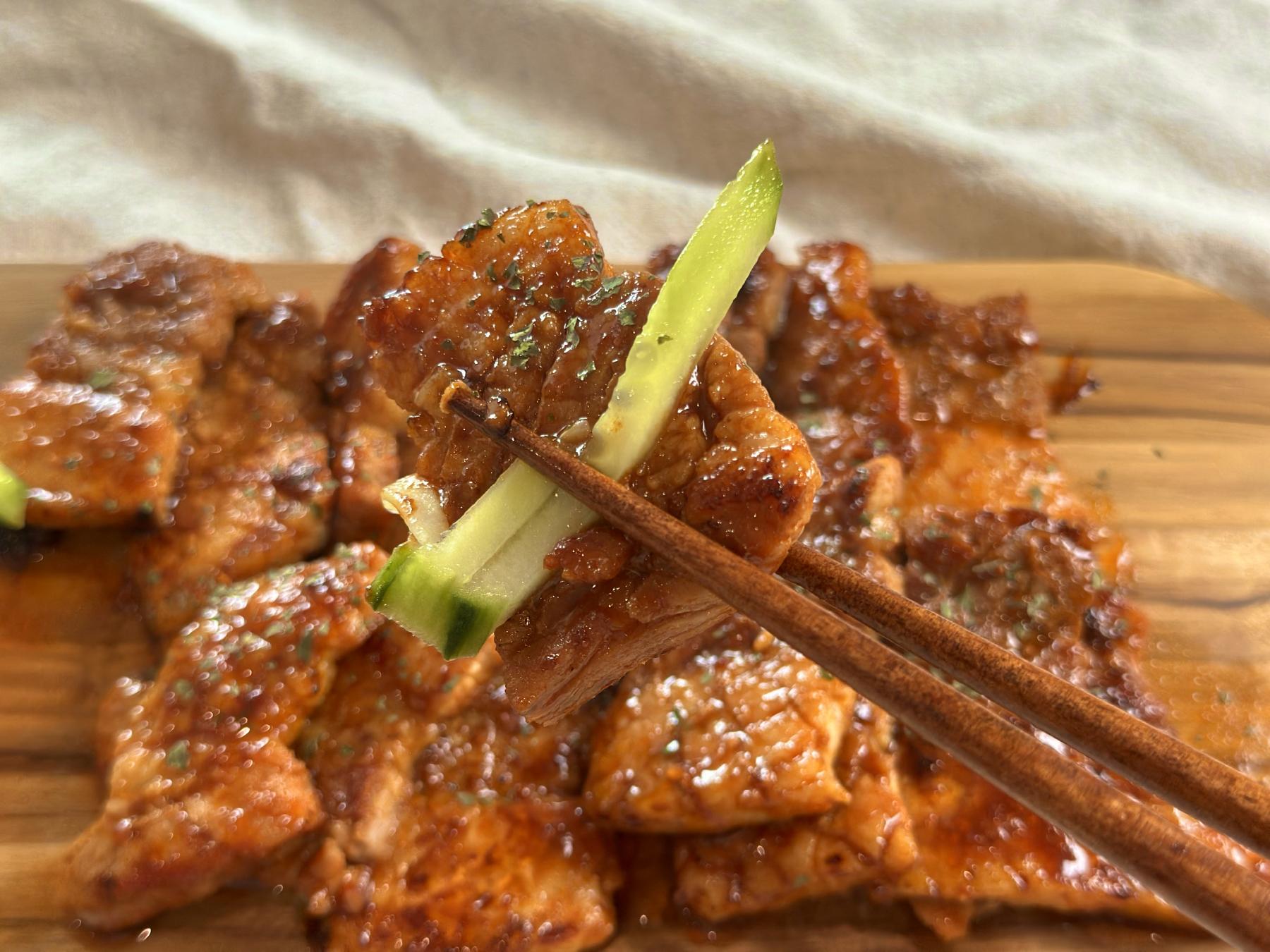 holding gochujang pork belly with chopsticks