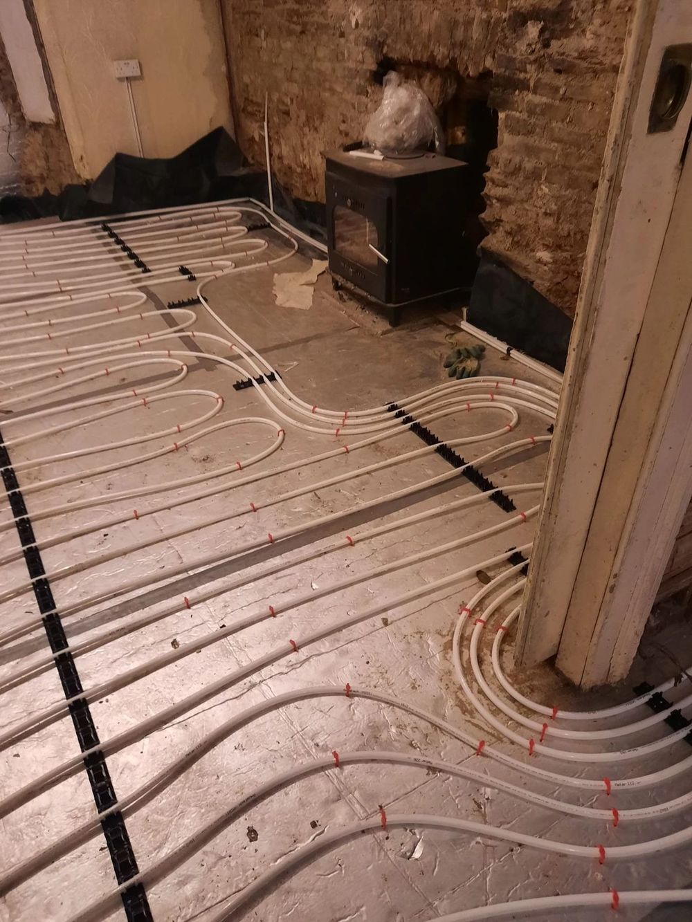 Underfloor heating pipes laid around a stove position