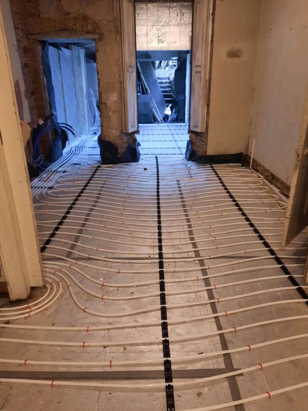 Underfloor heating pipes running through doorways in an old house