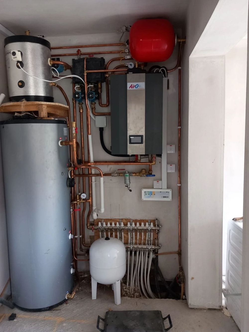 Finished plant room with cylinder, heat pump unit, manifold and red expansion vessel