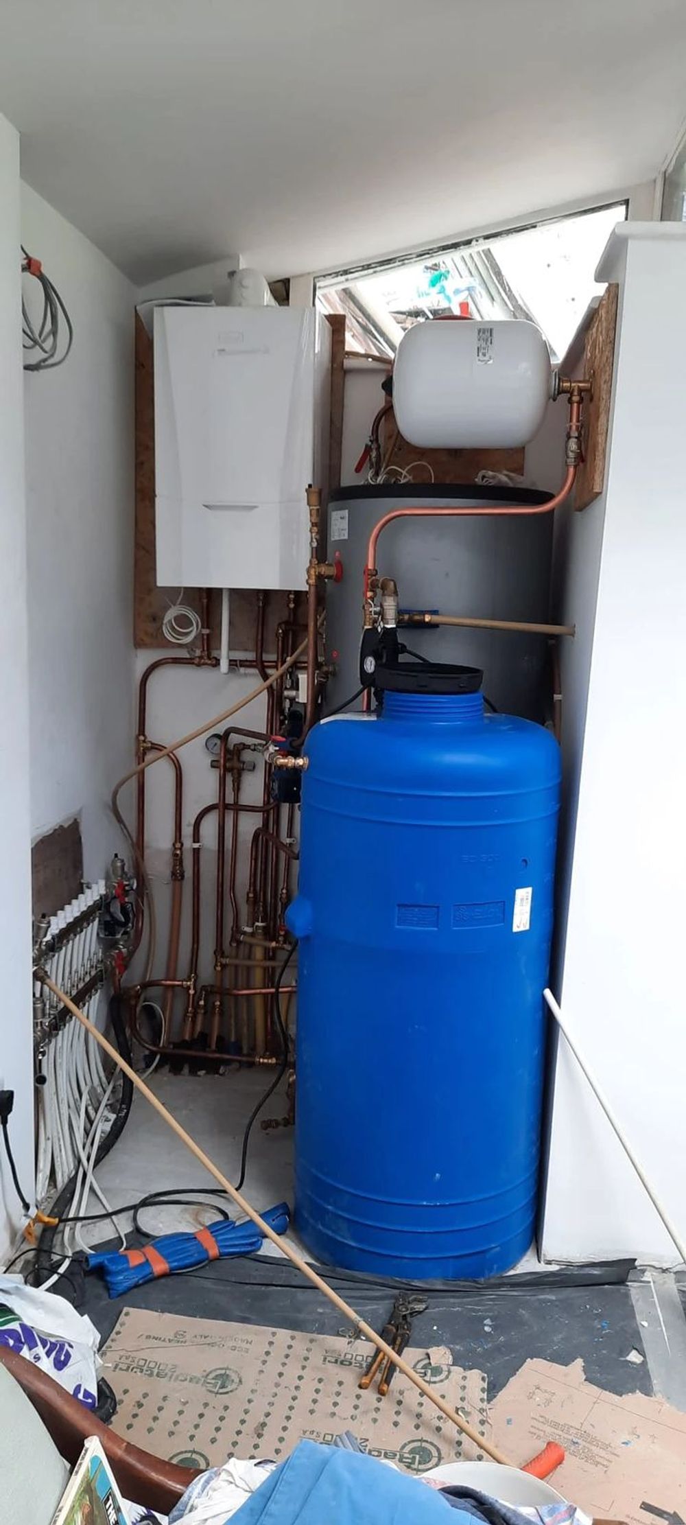 Hot water cylinder room with blue water tank and copper pipework