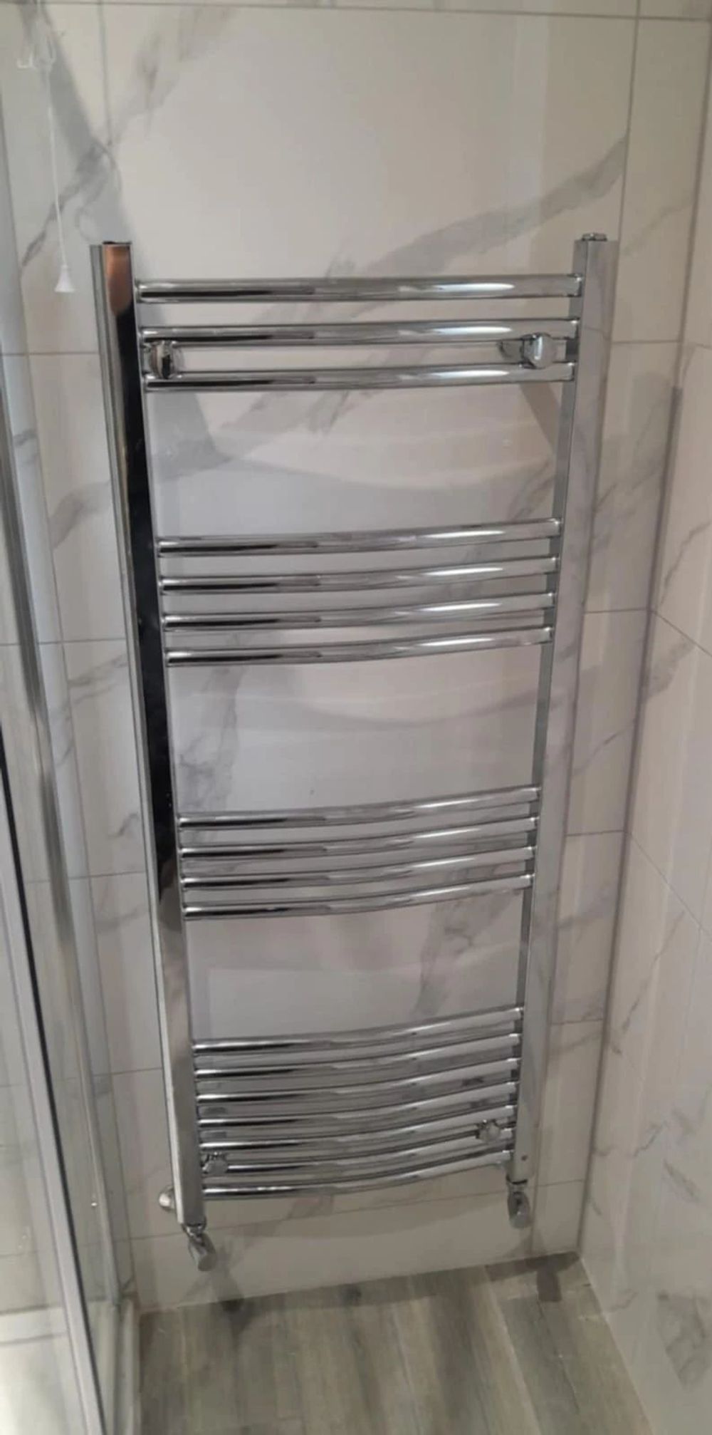 Chrome towel rail fitted on marble-effect bathroom tiles