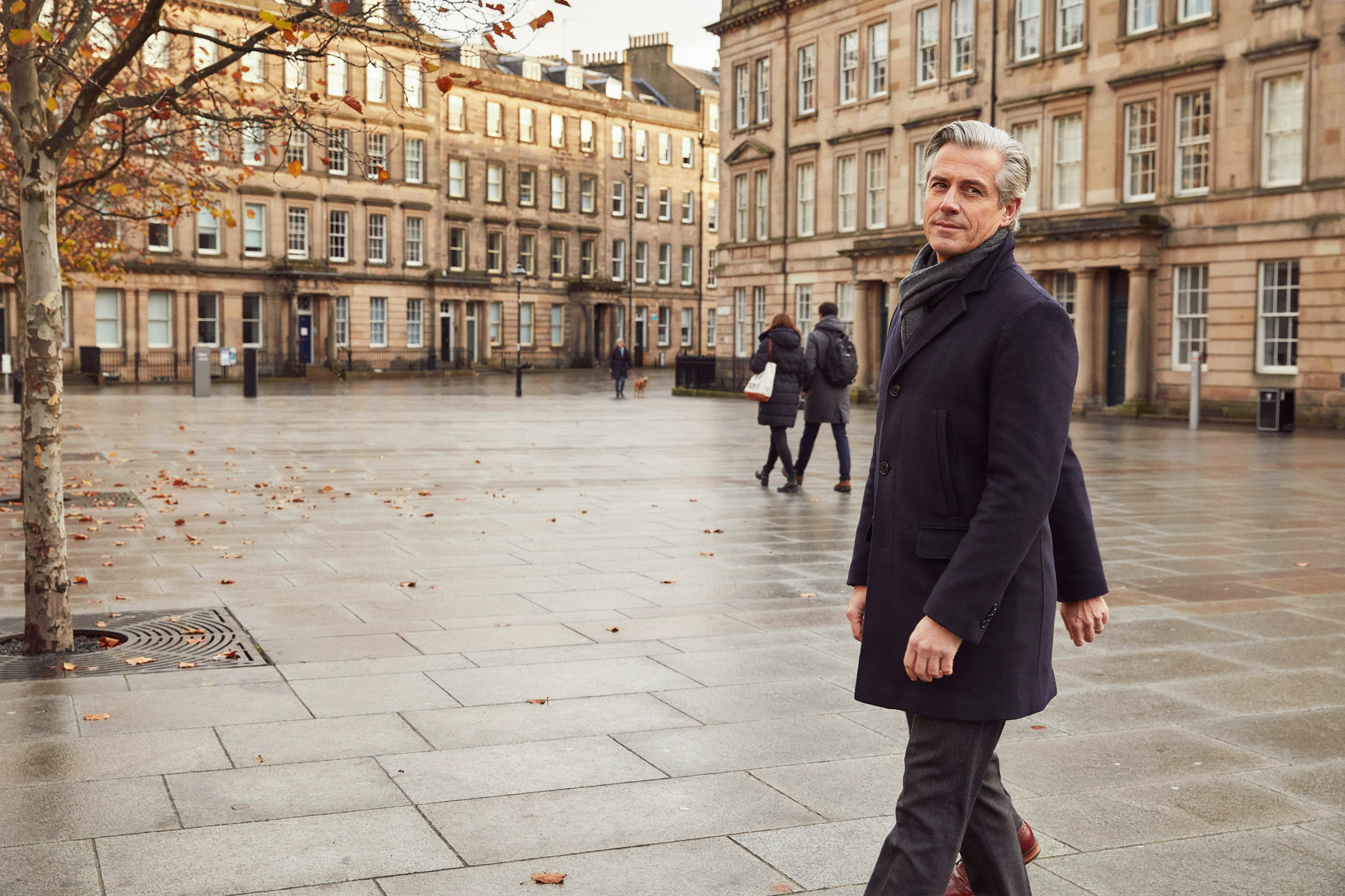 Man crossing a square in central Edinburgh on an autumn afternoon