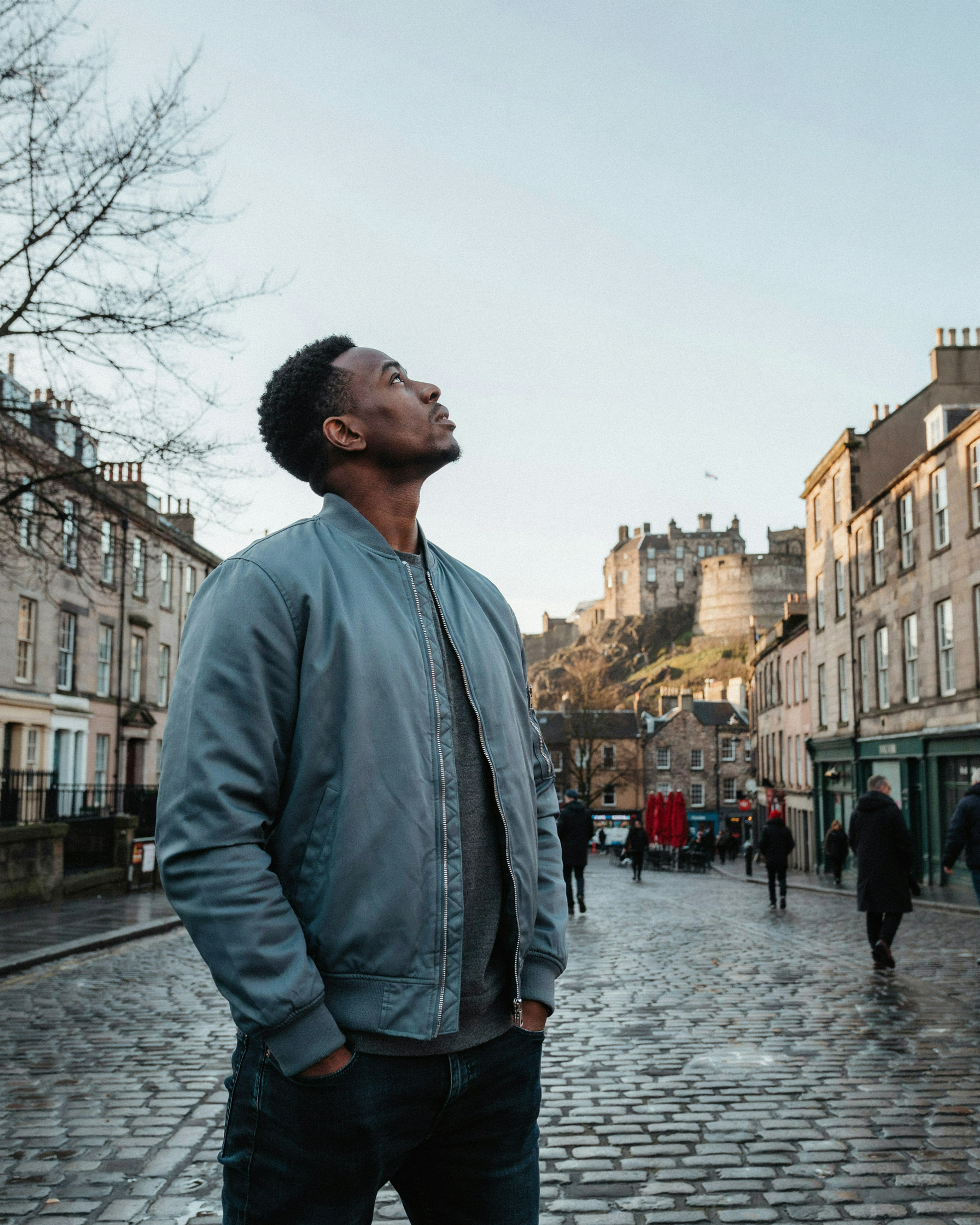 Man in the Grassmarket in Edinburgh on a winter day with the castle above