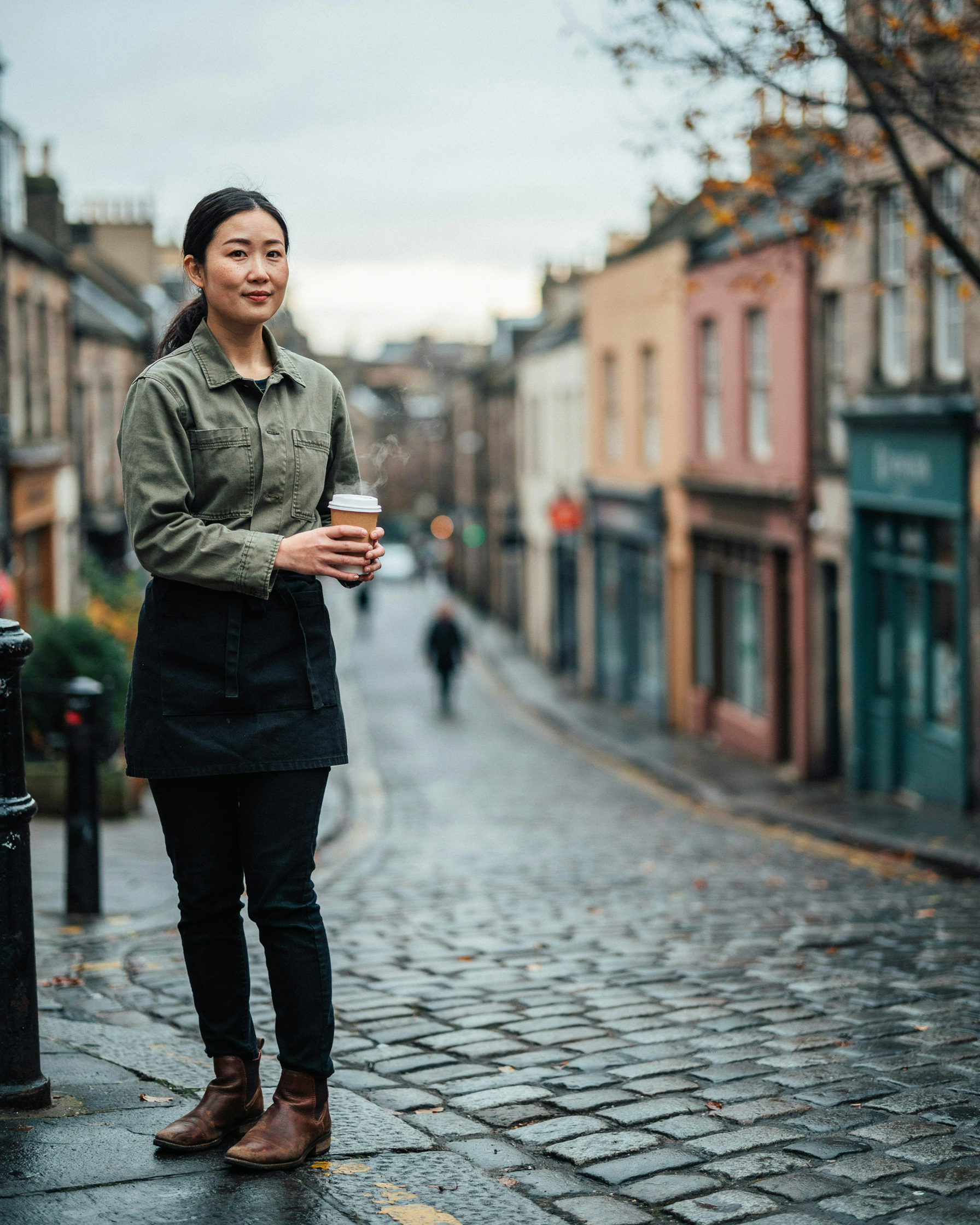 Hospitality worker walking to work along a cobbled Old Town street in Edinburgh on an autumn morning