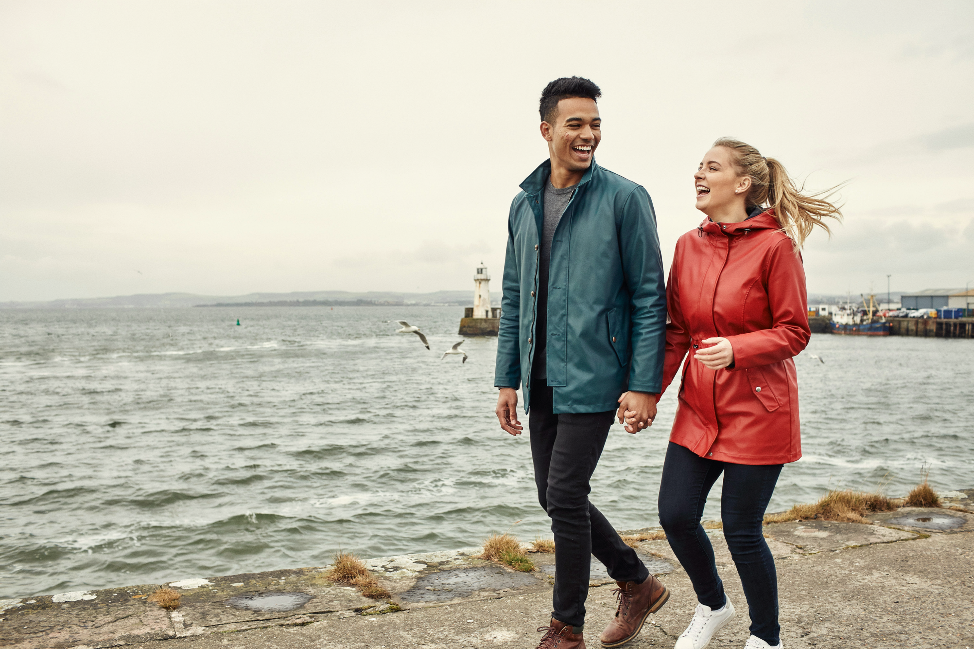 Two international students walking by Newhaven harbour in Edinburgh on a breezy autumn day