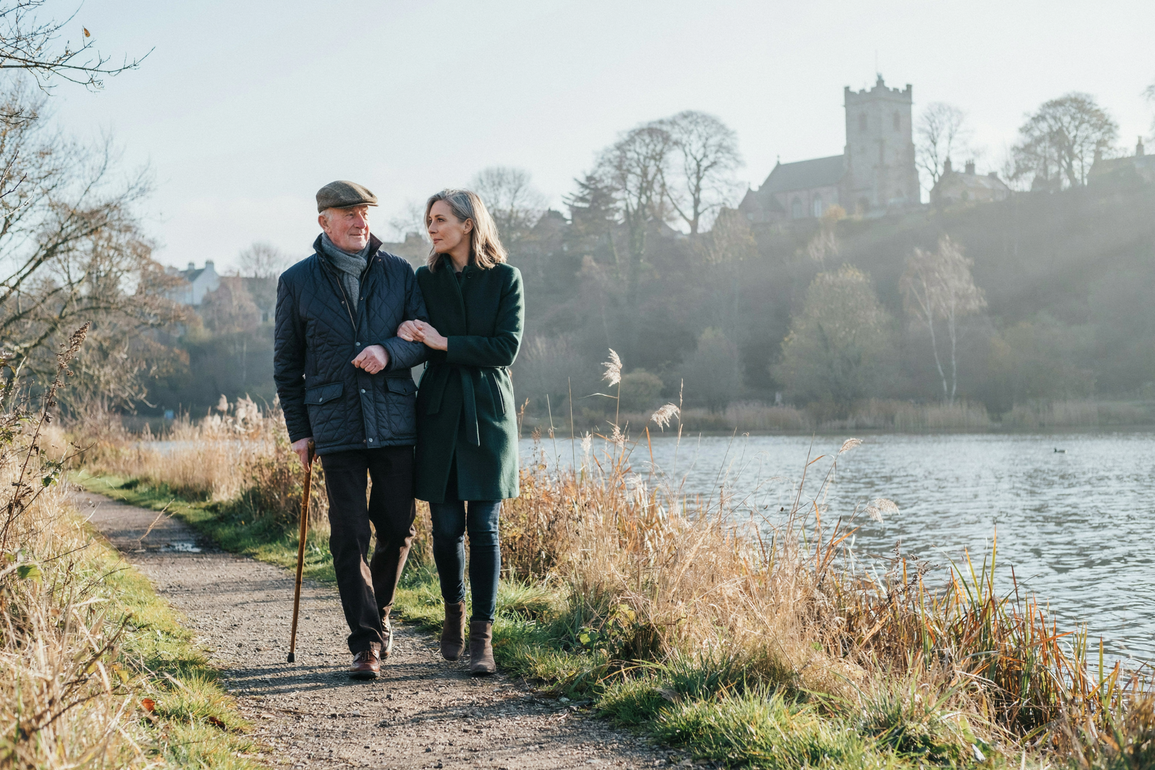 Older man walking with his daughter beside Duddingston Loch in Edinburgh in winter
