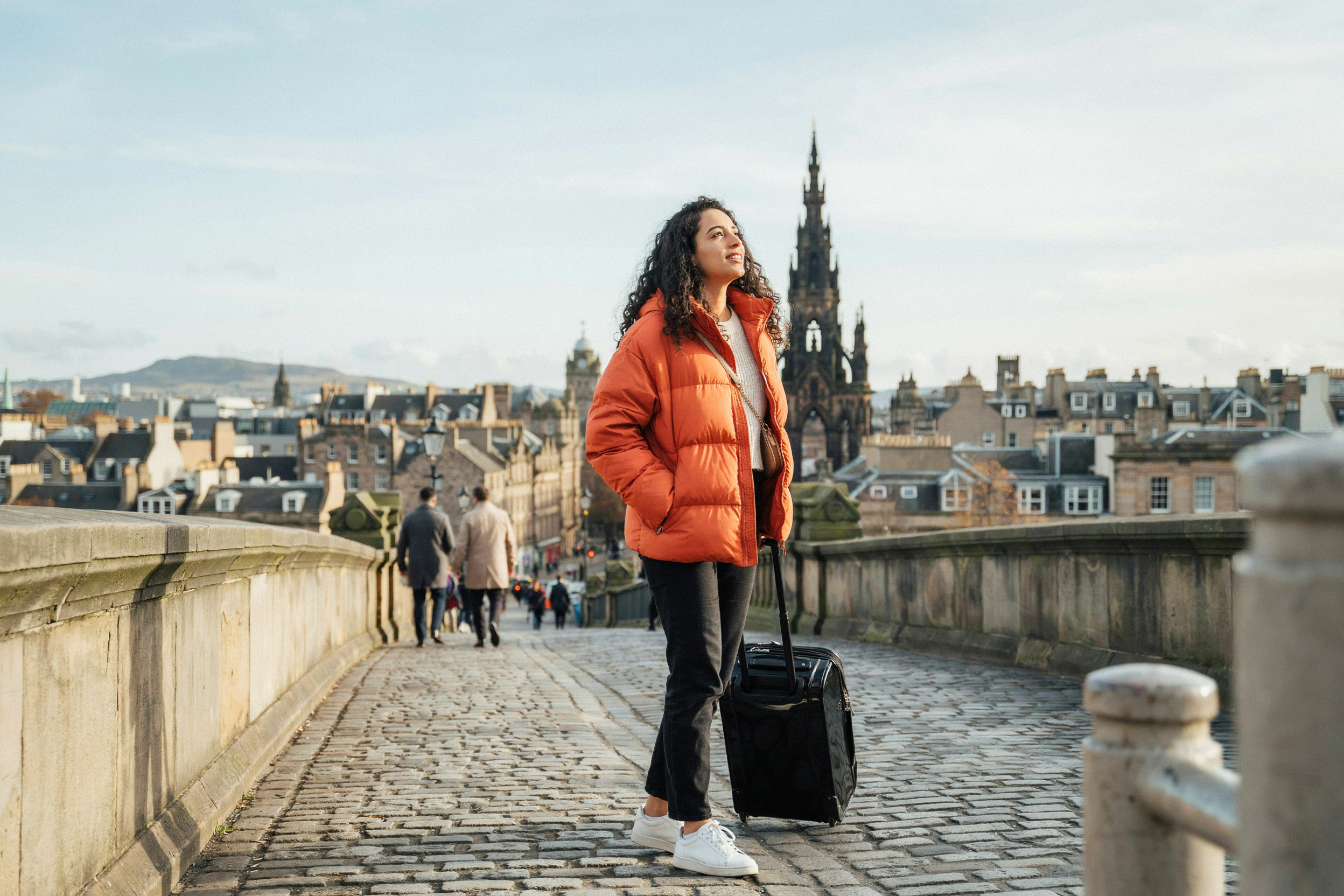 International student with a suitcase crossing Waverley Bridge, Edinburgh, on arrival in September