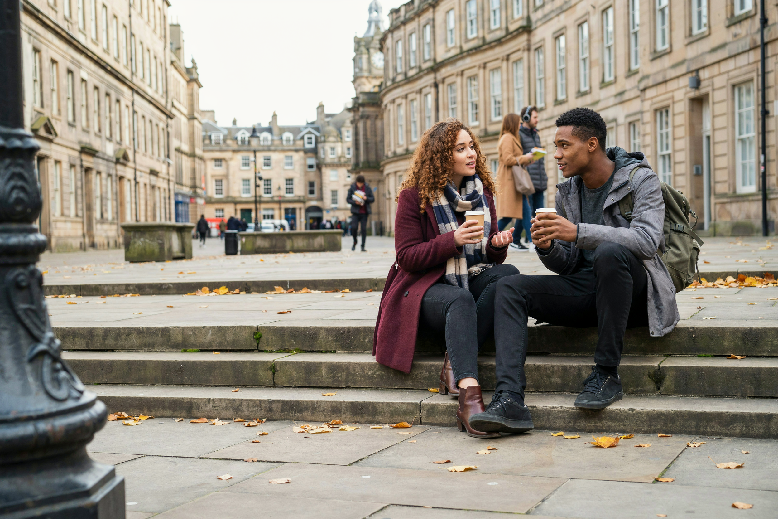 Two students sitting on stone steps in a university square in central Edinburgh