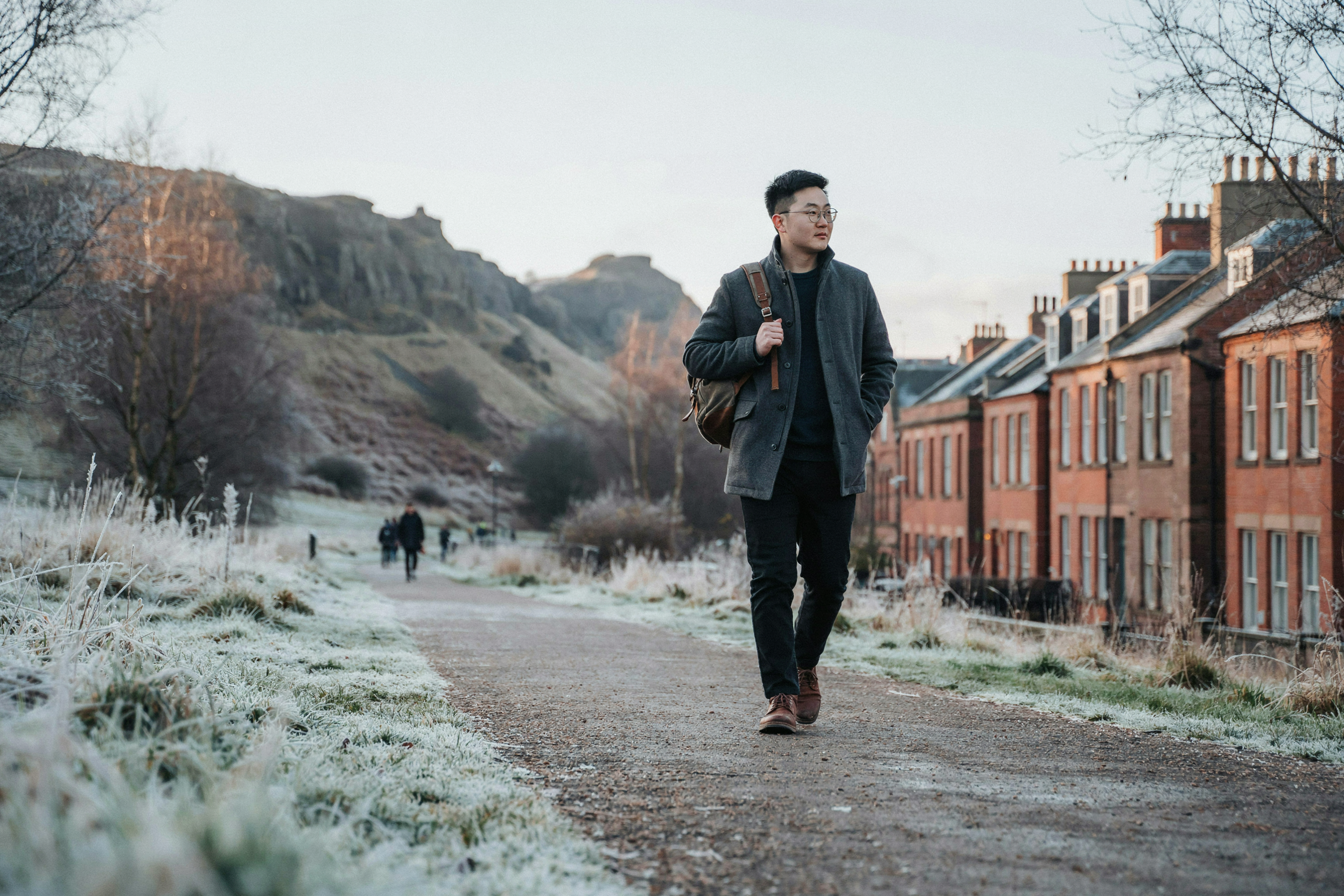 Student walking below Arthur's Seat near student residences in Edinburgh on a frosty morning